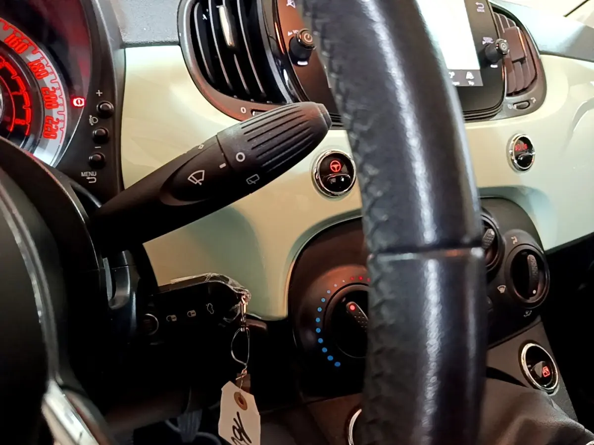 Gros plan sur le tableau de bord vert clair et le volant cuir noir de la Fiat 500 2019 version Lounge.