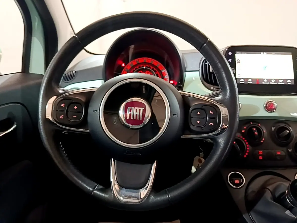 Vue intérieure centrée sur le volant cuir noir de la Fiat 500 Lounge vert avec tableau de bord et écran tactile.