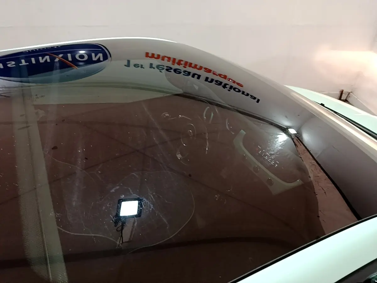 Vue plongeante sur l'intérieur d'une FIAT 500 verte, mettant en valeur le tableau de bord et le volant visibles à travers le pare-brise.