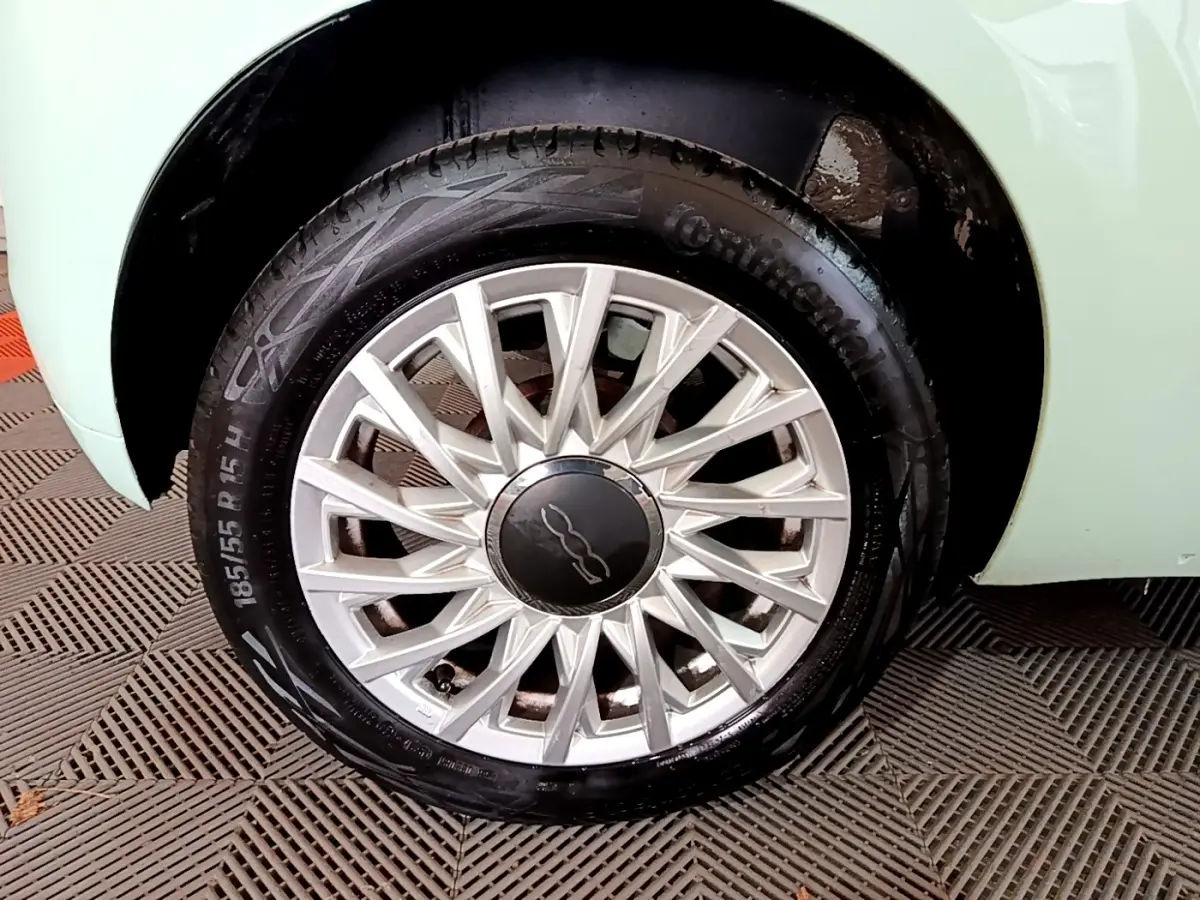 Gros plan sur la roue avant gauche d'une FIAT 500 verte, mettant en valeur la jante alu à rayons fins et le pneu Continental.