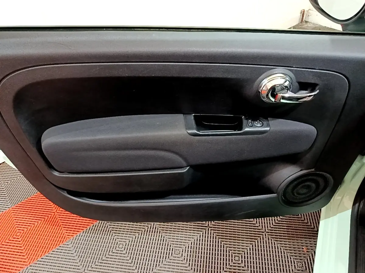 Intérieur de la porte côté conducteur d'une FIAT 500 Lounge 2019 vert, avec poignée chrome et commande vitres.