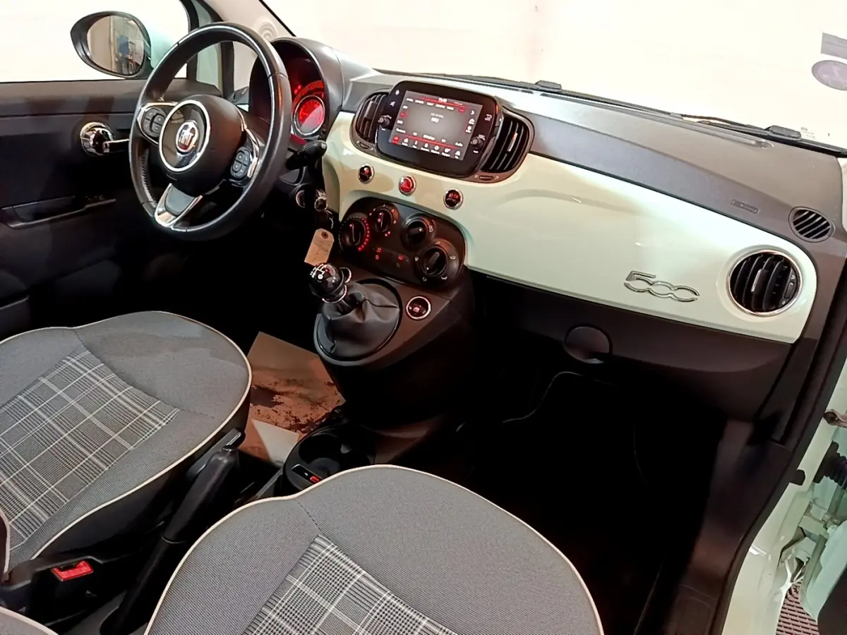 Intérieur avant droit de la Fiat 500 Lounge 2019 avec tableau de bord crème, volant cuir et écran tactile central.