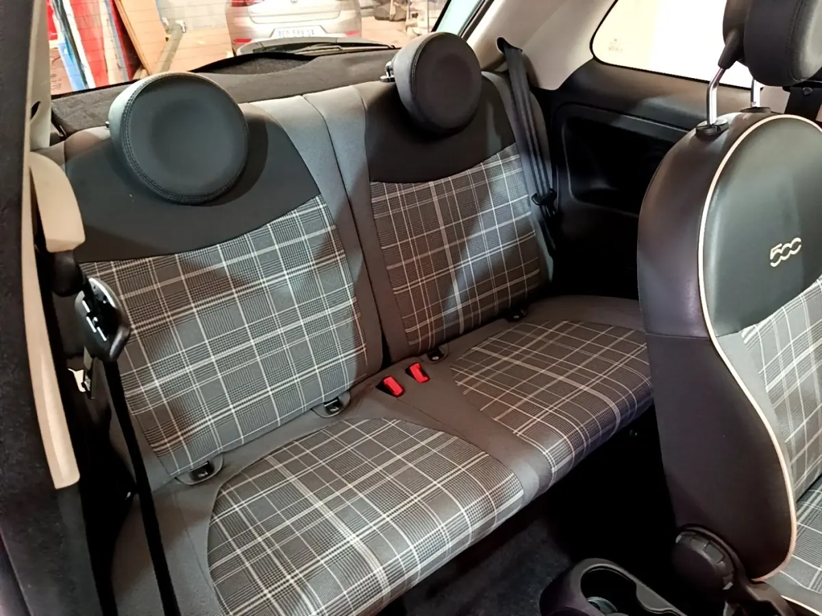 Vue intérieure du siège arrière et dossier à motif écossais gris de la Fiat 500 Lounge 2019, avec appuie-têtes ronds noirs.