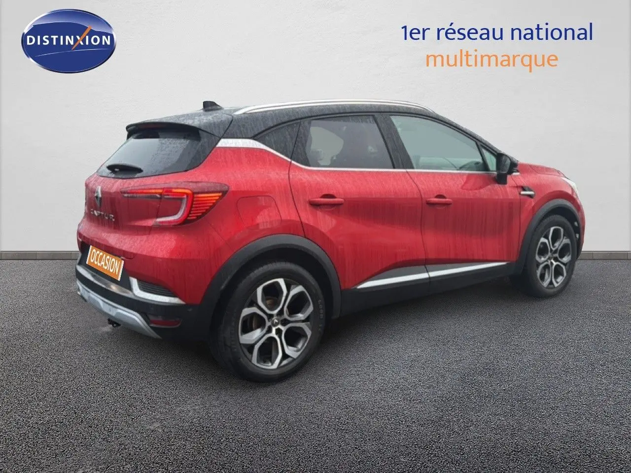 Vue 3/4 arrière droite d’un Renault Captur rouge flamme avec toit noir et jantes bi-ton distinctives.