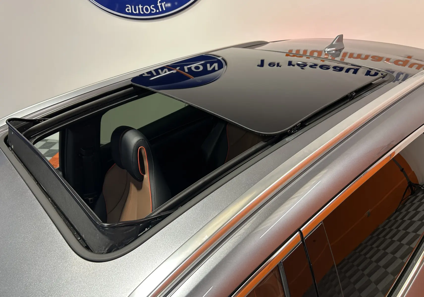 Vue en plongée du toit ouvrant ouvert sur BYD SEAL U gris métallisé avec intérieur cuir marron et surpiqûres orange.