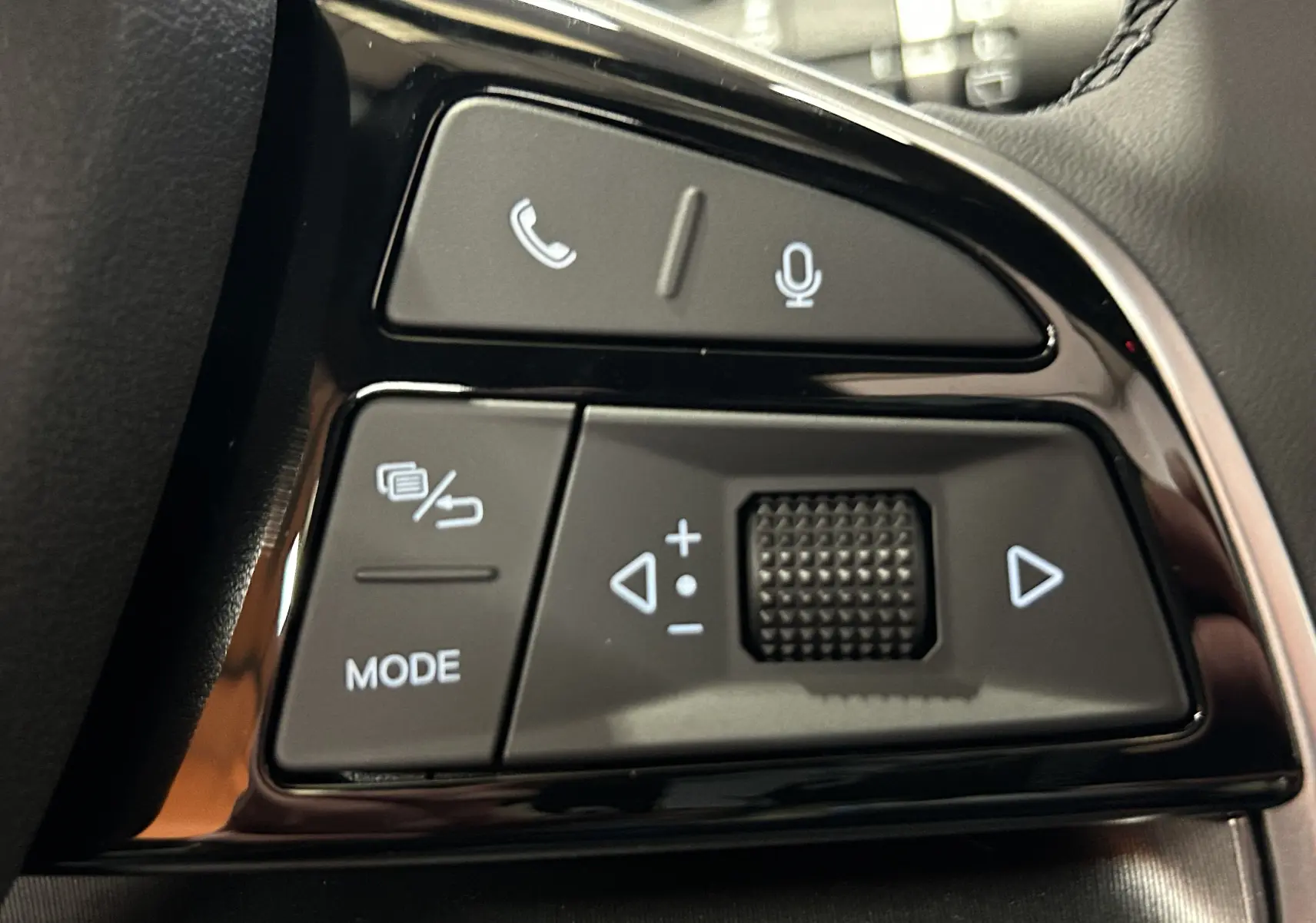 Gros plan sur les commandes au volant noir brillant du BYD SEAL U 2025, avec boutons téléphone, micro et mode.