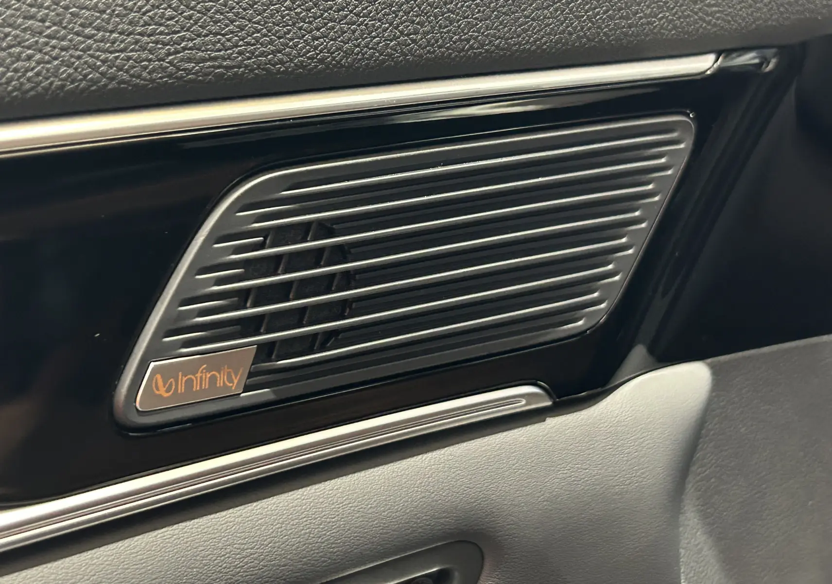 Gros plan sur le haut-parleur Infinity intégré dans la porte intérieure du BYD SEAL U, finition cuir marron visible.