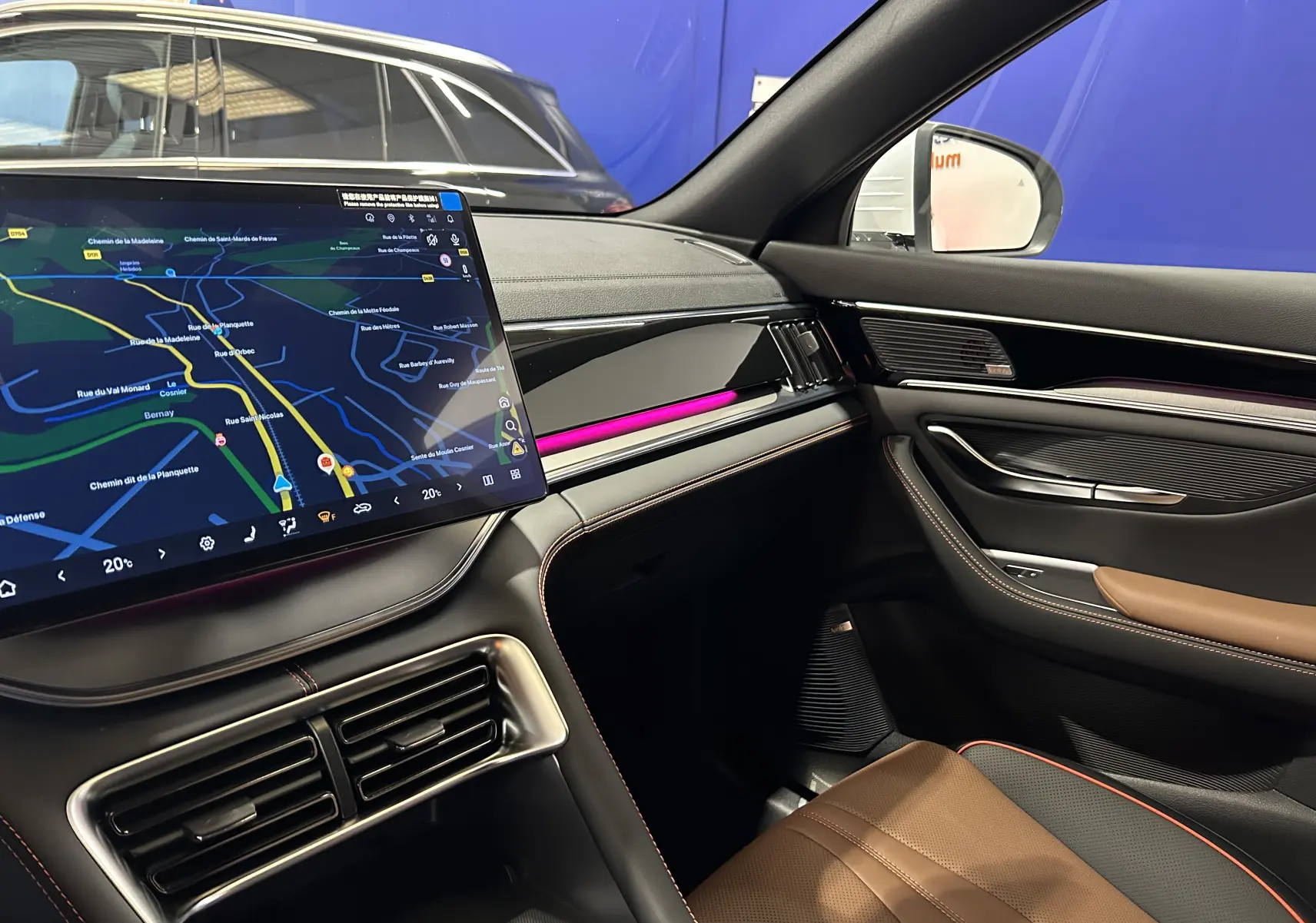 Vue intérieure côté passager du BYD SEAL U 2025, avec écran tactile, éclairage d'ambiance violet et sellerie cuir marron.