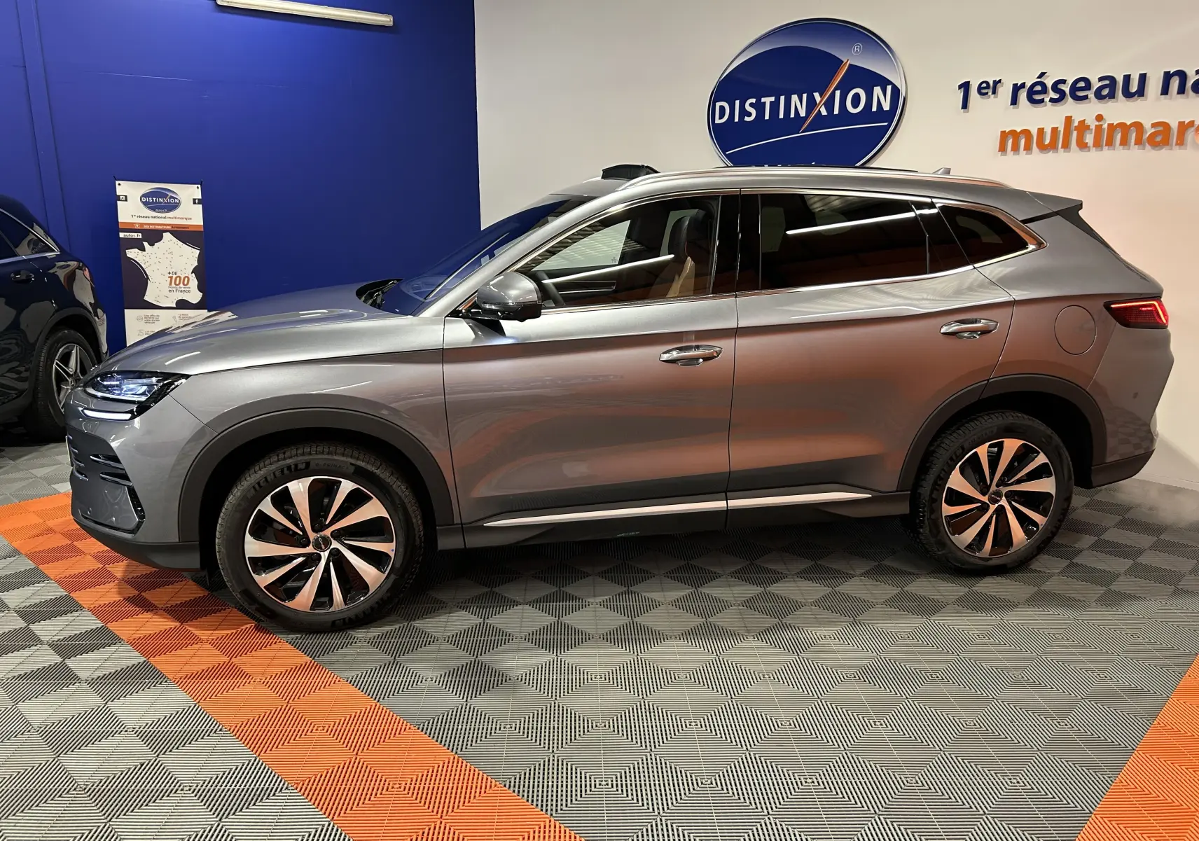 Vue de profil côté gauche d’un BYD SEAL U gris métallisé avec jantes bi-ton et vitres teintées en showroom.