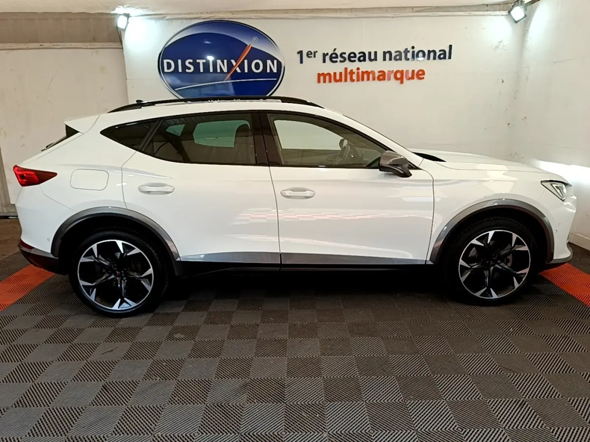 Profil droit d'un CUPRA Formentor blanc 2023 avec jantes noires et logo Distinxion en arrière-plan.