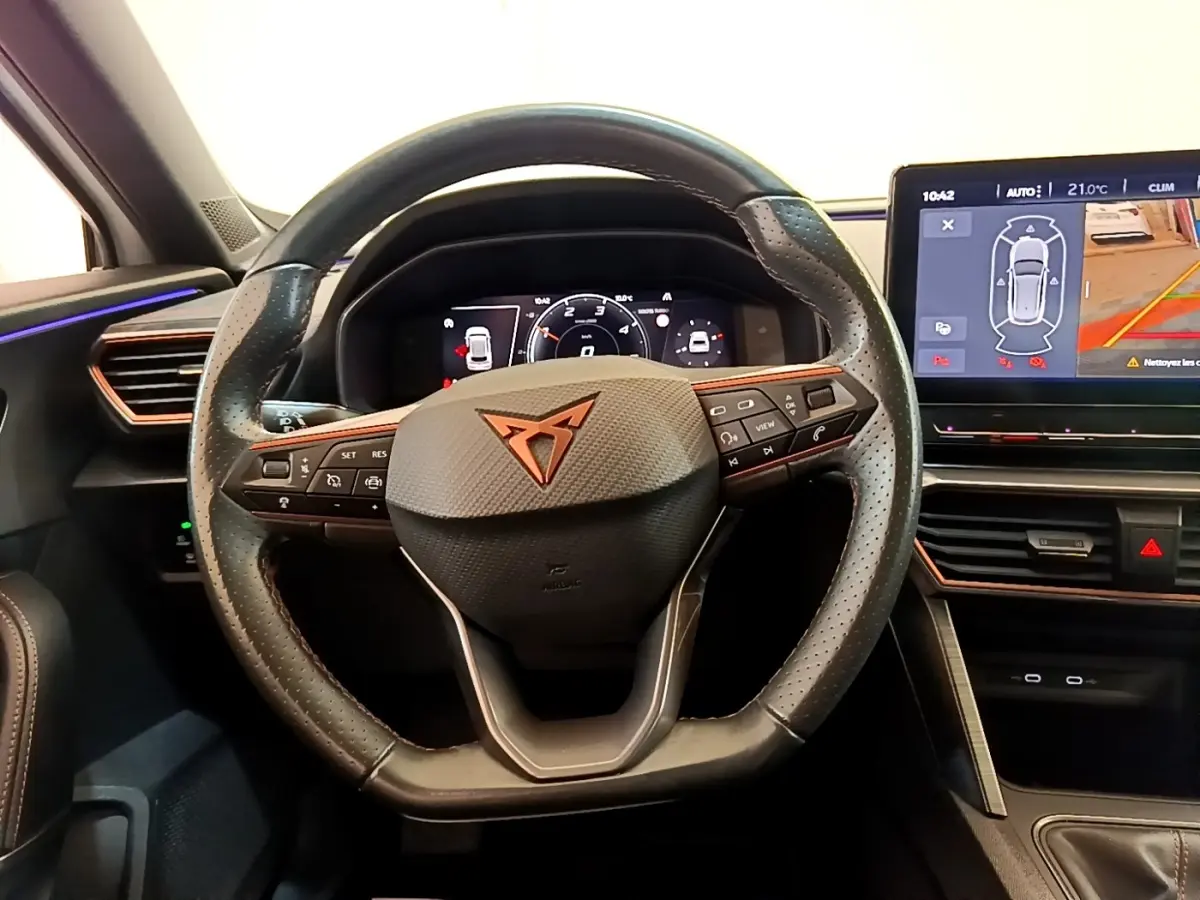 Vue intérieure centrée sur le volant cuir perforé noir avec logo CUPRA et tableau de bord numérique lumineux.