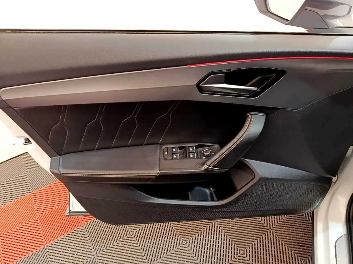 Vue intérieure côté gauche de la porte avant d’une CUPRA Formentor 2023 avec garniture noire et éclairage d’ambiance rouge.