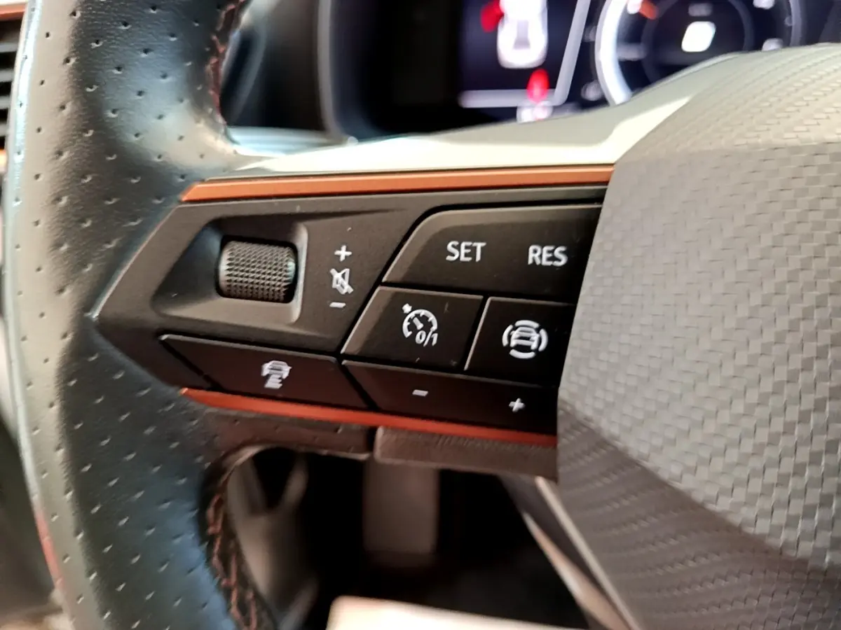 Gros plan sur les commandes du volant cuir noir perforé du CUPRA Formentor 2.0 TDI 2023 avec boutons multifonctions.