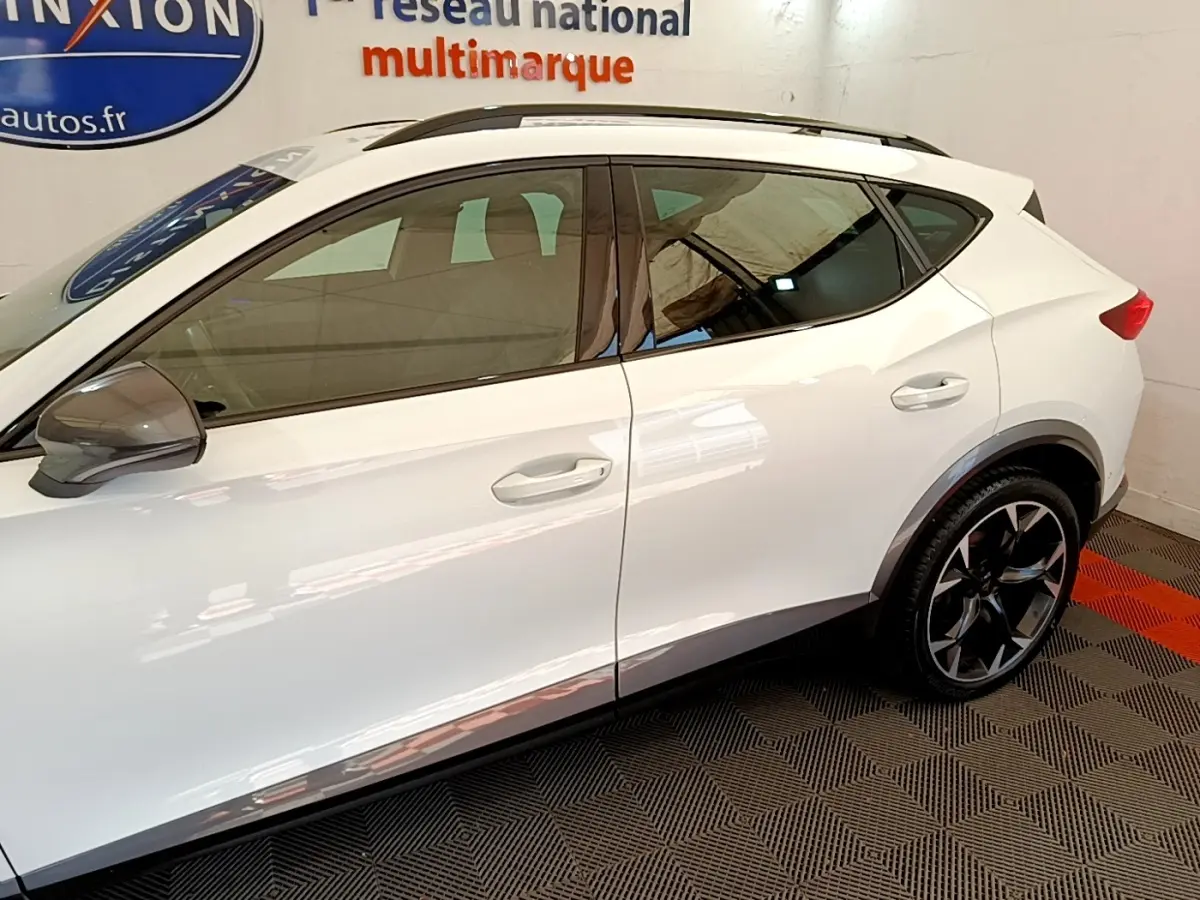 Vue latérale droite du CUPRA Formentor blanc avec jantes noires et rétroviseurs gris dans un showroom.