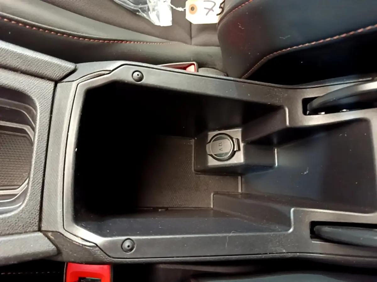 Vue rapprochée de la console centrale noire du CUPRA Formentor 2023 avec prise 12V visible et surpiqûres rouges sur les sièges.