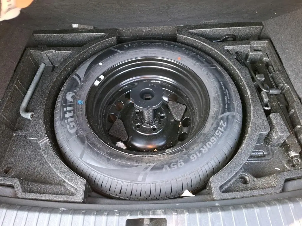 Gros plan sur la roue de secours et les outils de bord du coffre d'un Skoda Karoq gris 2023.