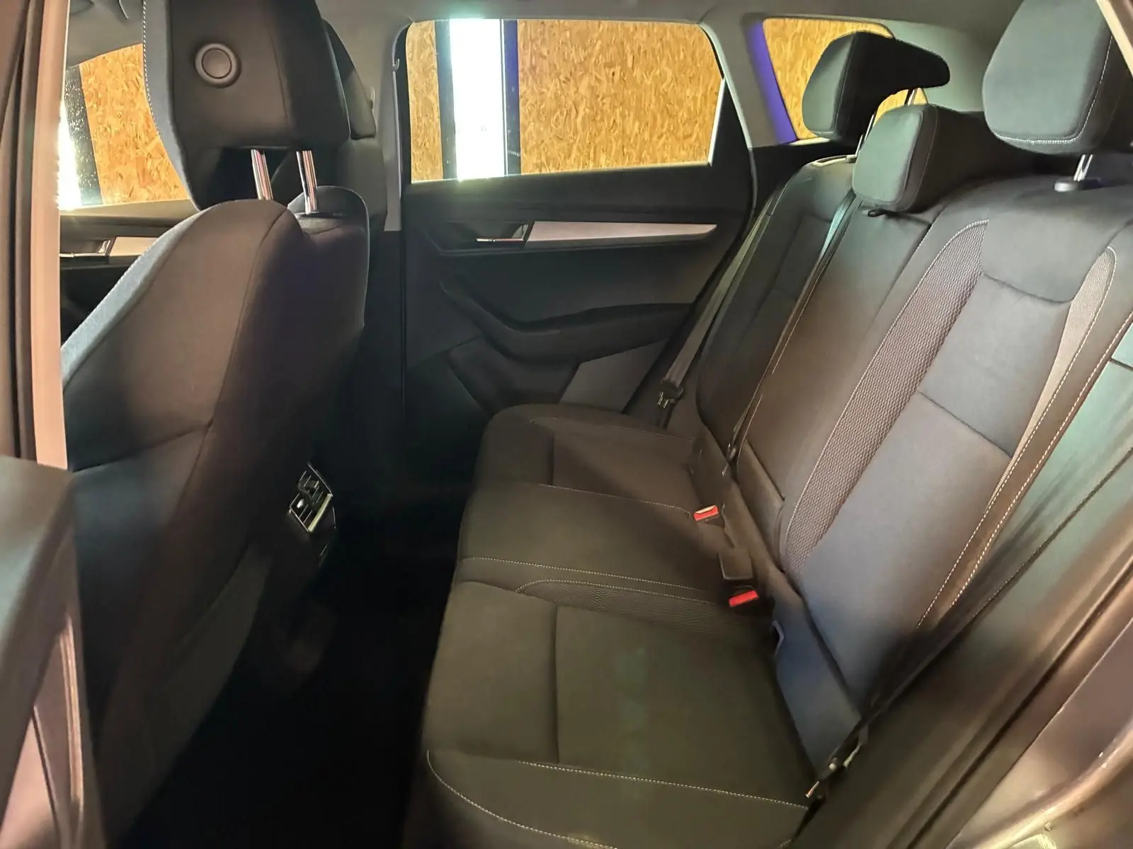 Vue intérieure côté droit des sièges arrière noirs du Skoda Karoq 2023 avec finitions tissu et ceintures visibles.