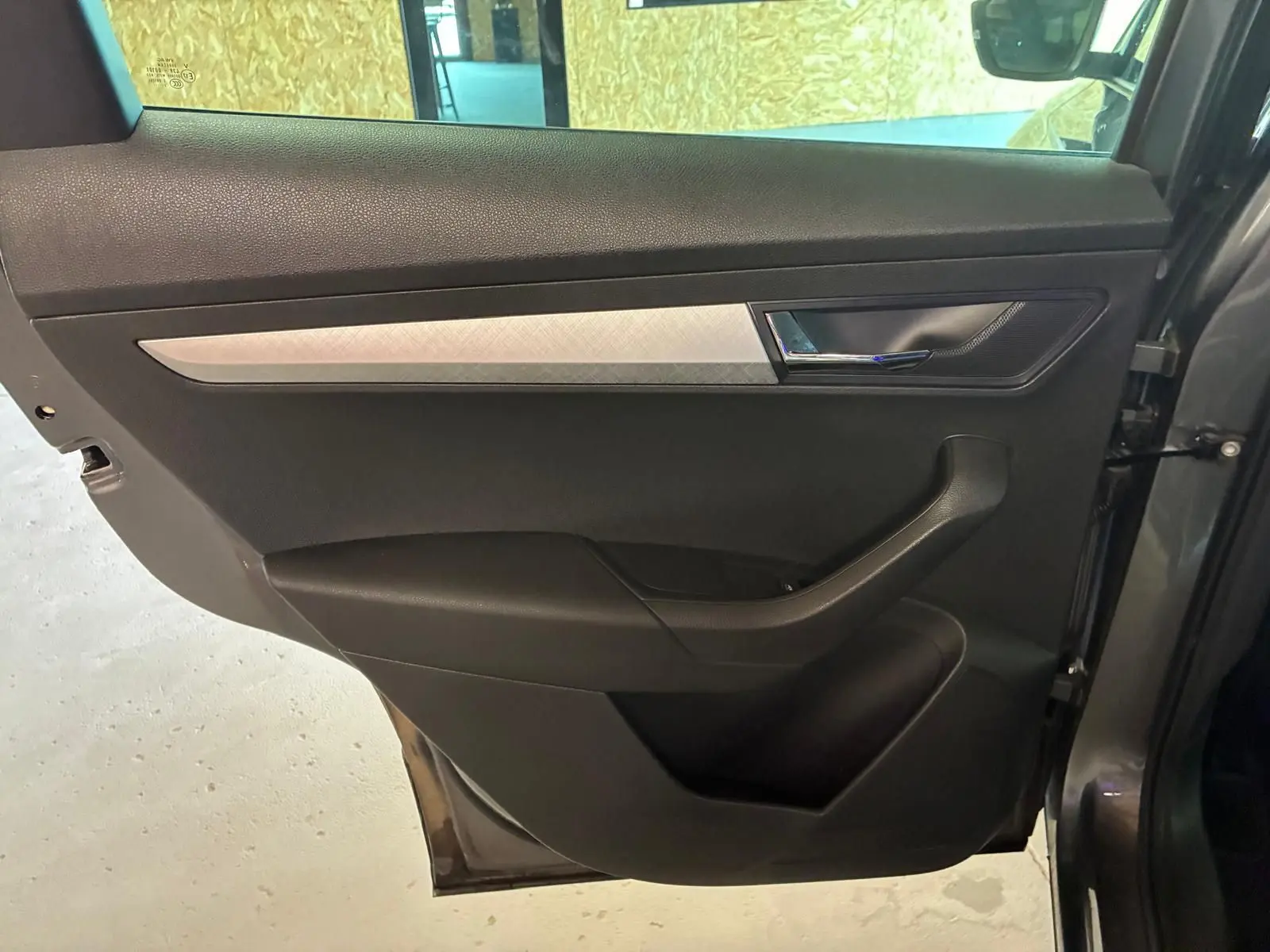 Porte arrière droite gris foncé de Skoda Karoq 2023 avec insert décoratif argenté et poignée chromée.