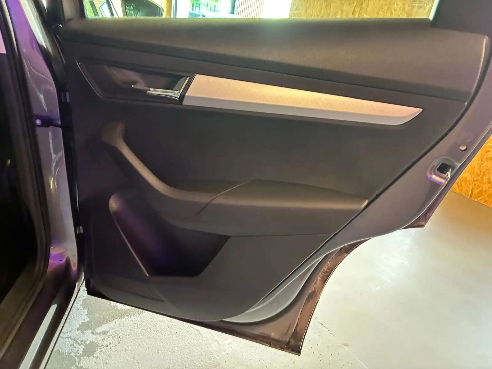 Vue intérieure de la porte arrière gauche gris foncé du Skoda Karoq 2023 avec poignée argentée et rangement intégré.