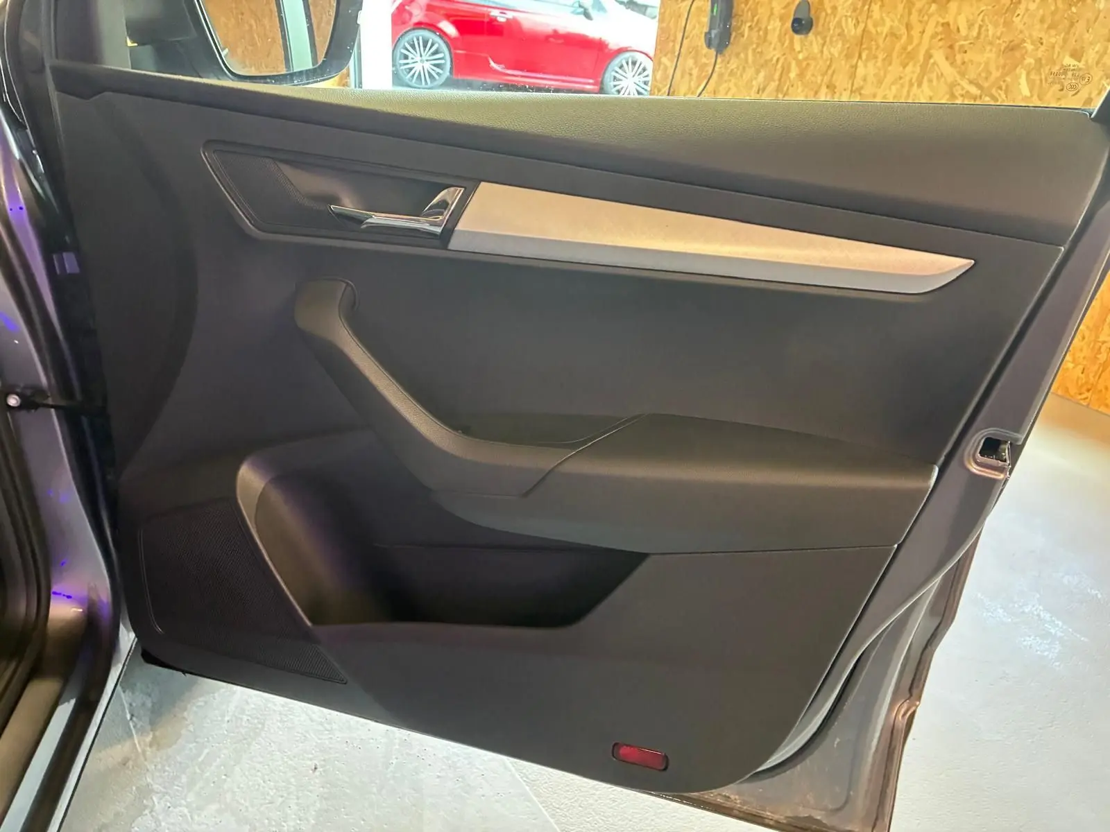 Vue intérieure de la porte avant gauche d’un Skoda Karoq gris, avec insert décoratif clair et poignée chromée.