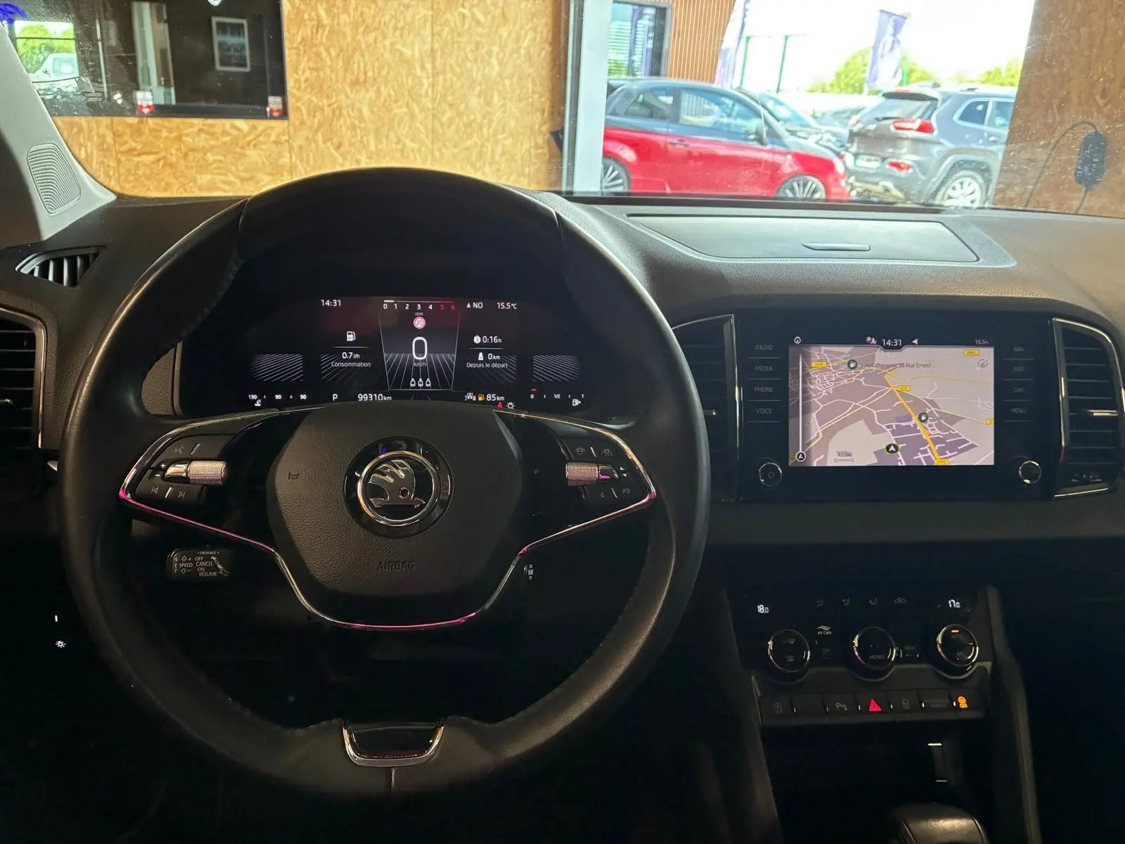 Vue intérieure centrée sur le volant cuir multifonctions et l’écran tactile du tableau de bord du Skoda Karoq gris 2023.