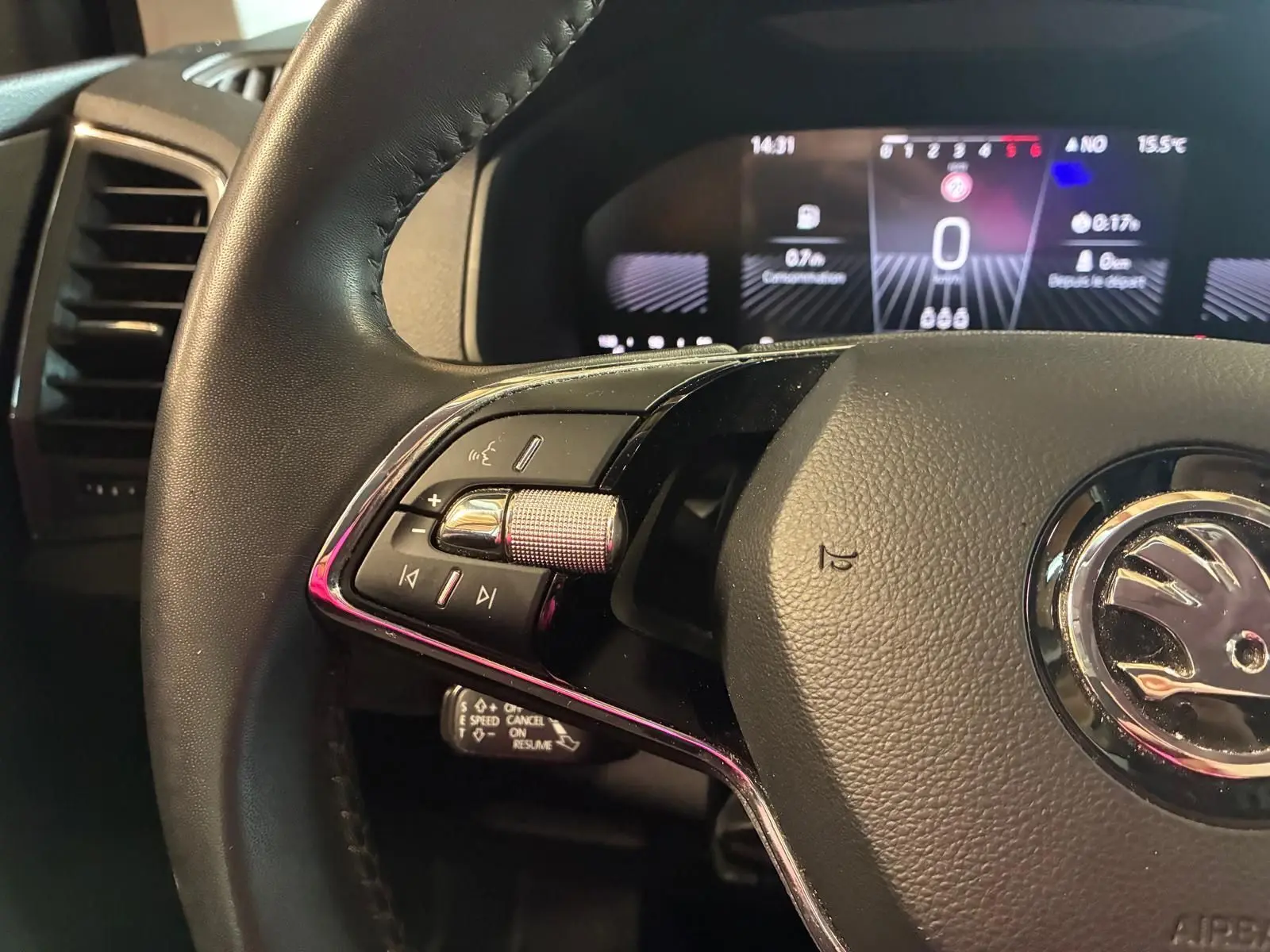 Gros plan sur le volant cuir multifonctions noir du Skoda Karoq 2023 avec tableau de bord digital en arrière-plan.