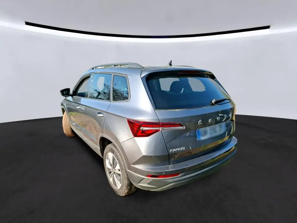 Vue 3/4 arrière droite d'un Skoda Karoq gris 2023 avec jantes alu 17 pouces et feux arrière LED distinctifs.