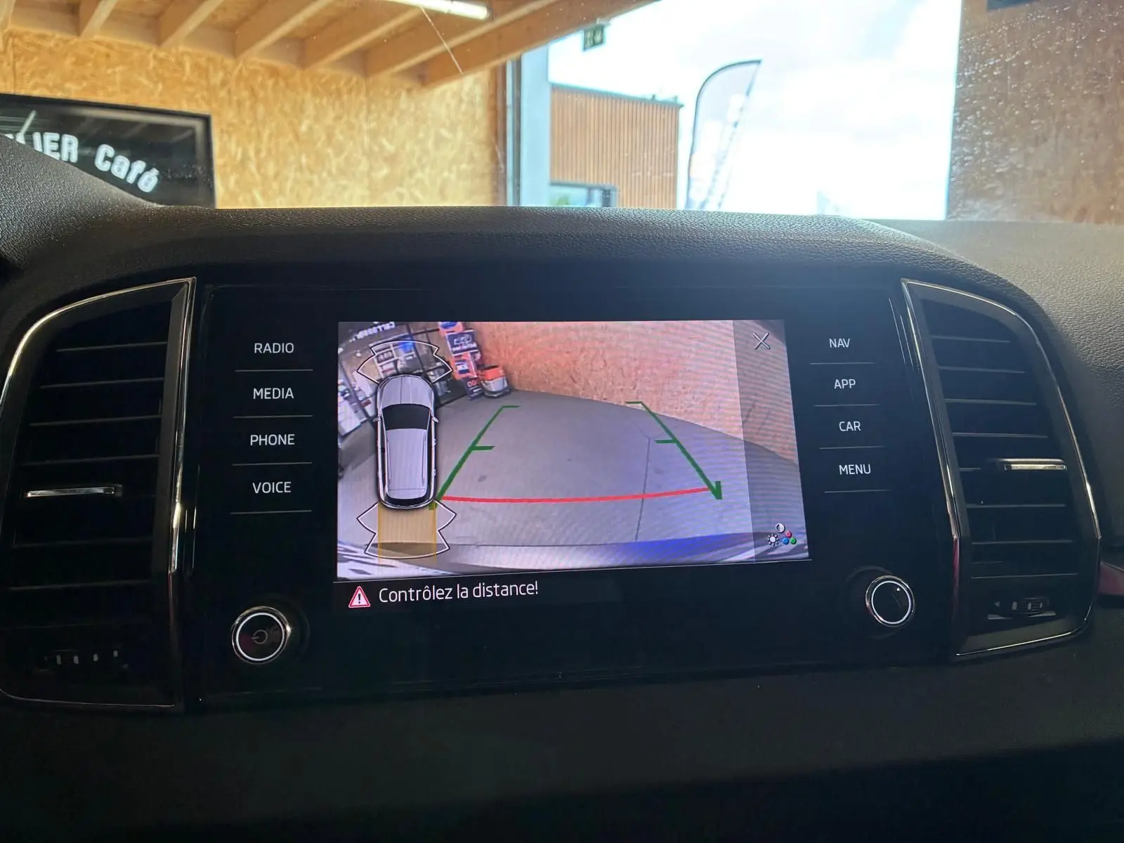 Écran central montrant la caméra de recul du Skoda Karoq gris avec aides au stationnement activées.