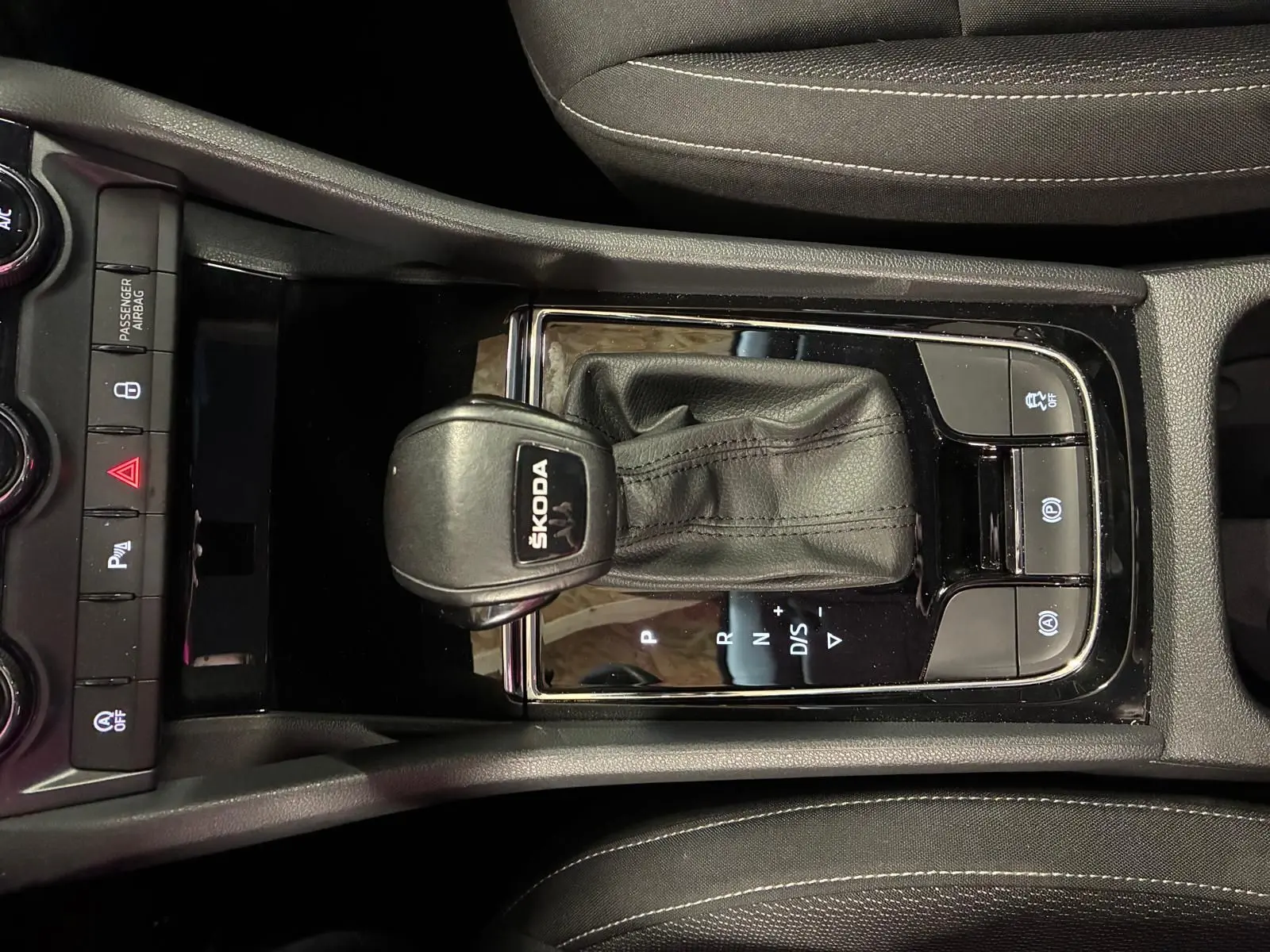 Vue rapprochée du levier de vitesses automatique noir marqué SKODA dans la console centrale du Skoda Karoq gris.