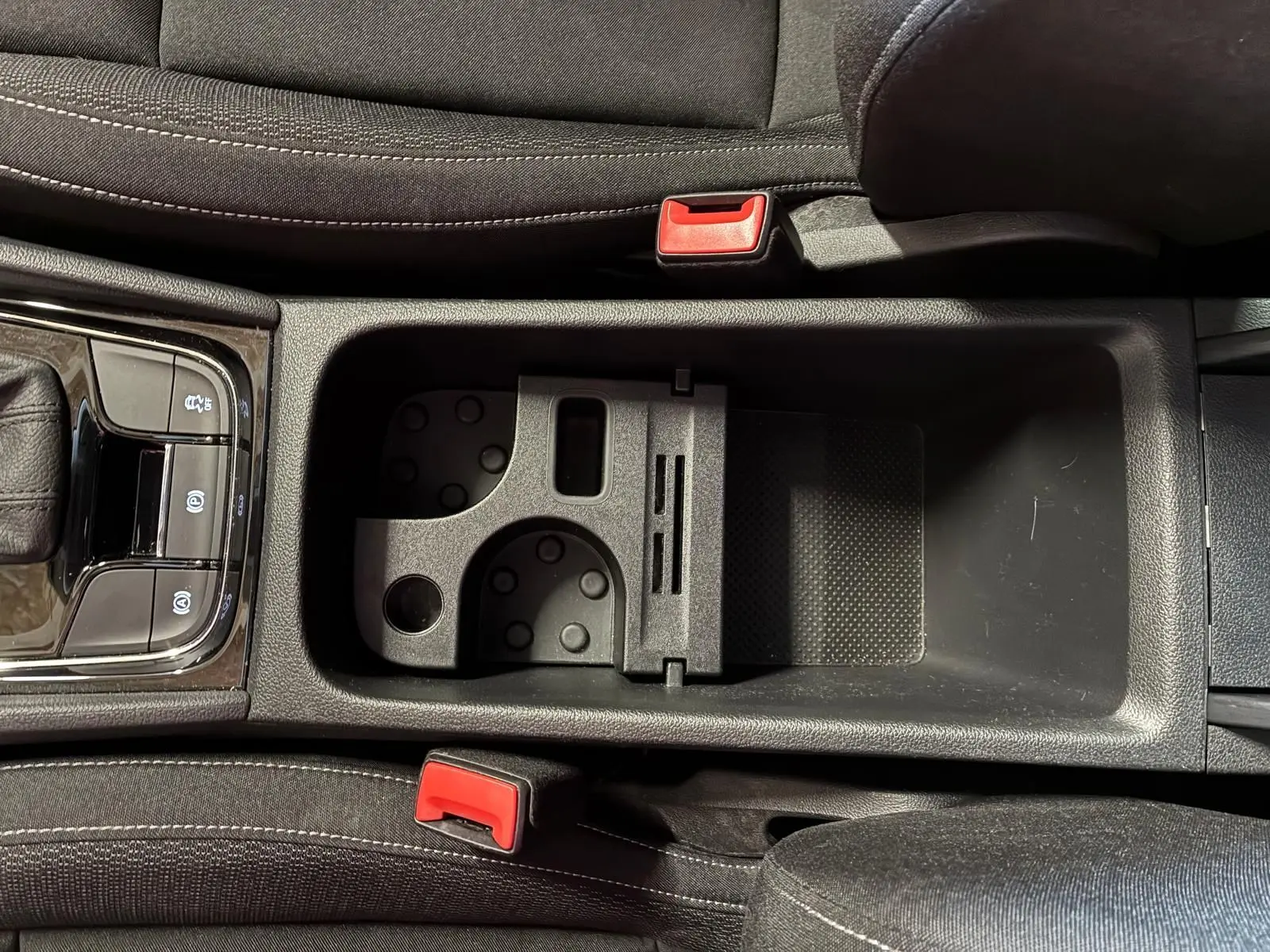 Vue plongeante sur la console centrale noire du Skoda Karoq 2023 avec porte-gobelets et frein à main électrique.