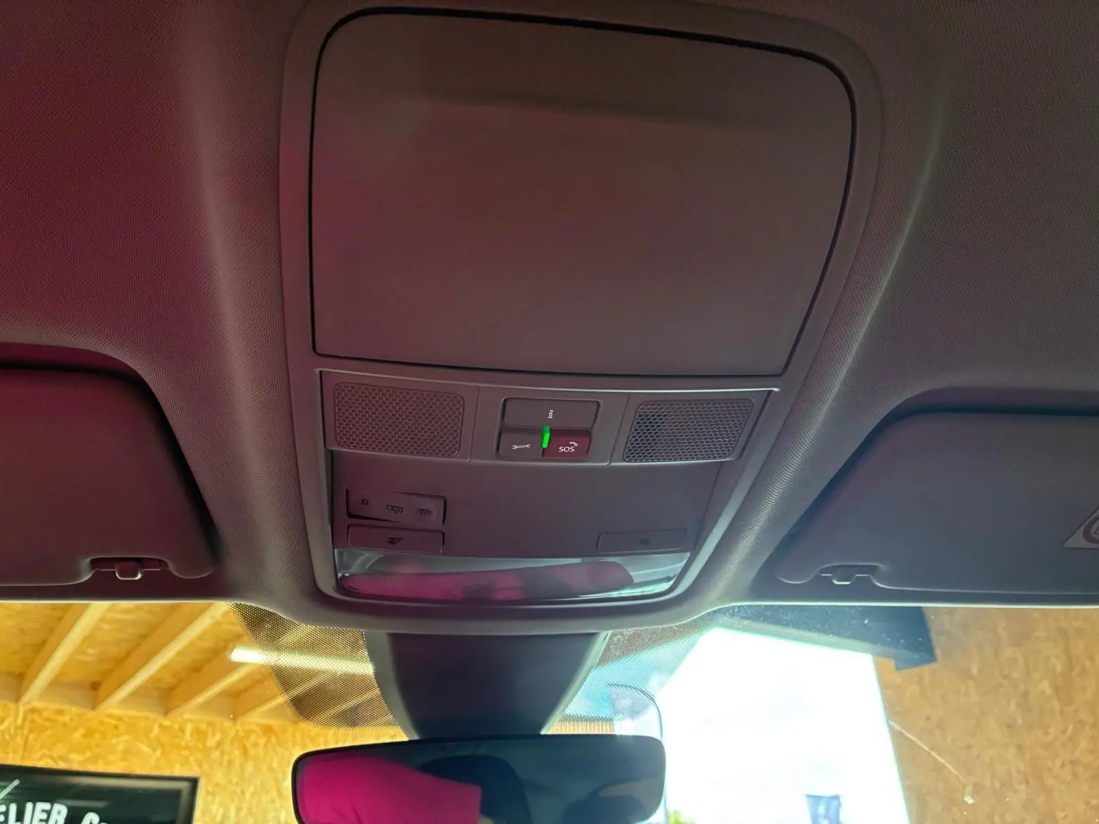 Vue intérieure du plafonnier avant du Skoda Karoq gris 2023, avec commandes d'éclairage et bouton SOS visible.