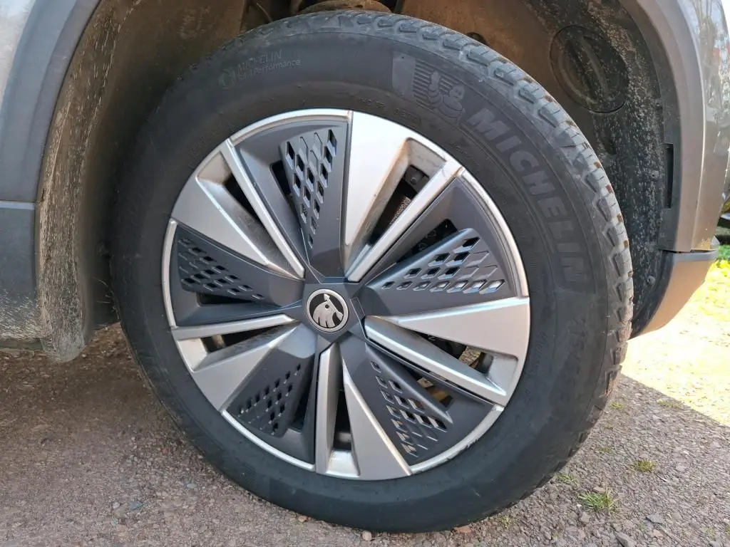 Gros plan sur la jante alu 17'' gris argent avec logo Skoda, montée sur un pneu Michelin d'un Skoda Karoq gris.
