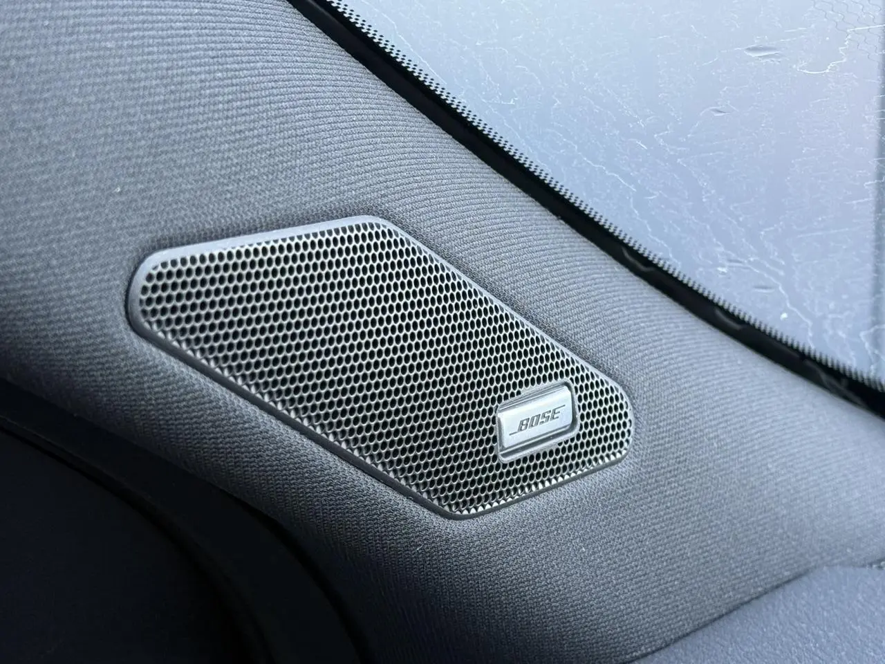 Gros plan sur l'enceinte Bose intégrée dans l'habitacle noir du Nissan Qashqai 2025.