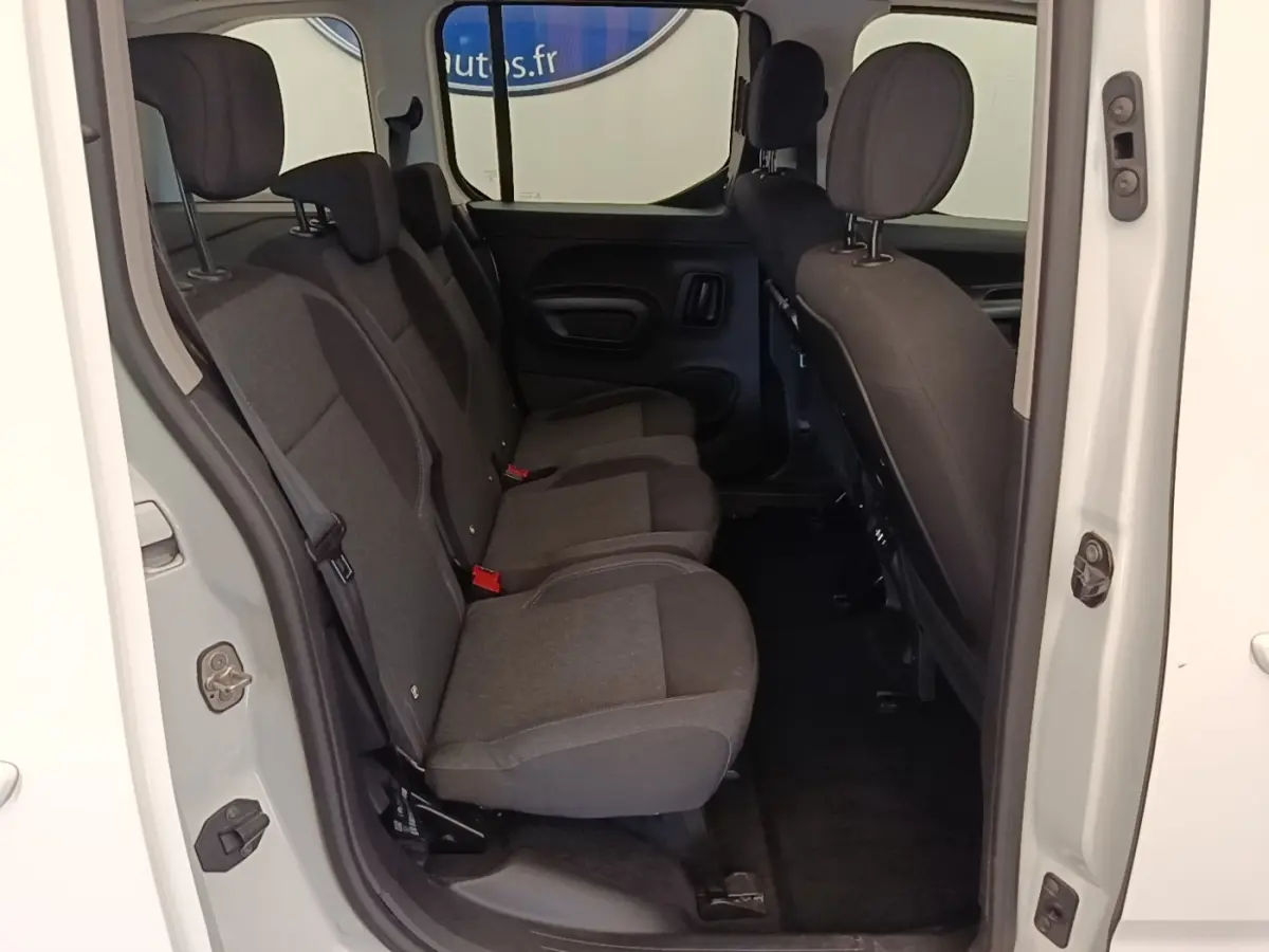 Vue intérieure côté droit sur la banquette arrière trois places du Peugeot Rifter blanc, sièges en tissu gris foncé.