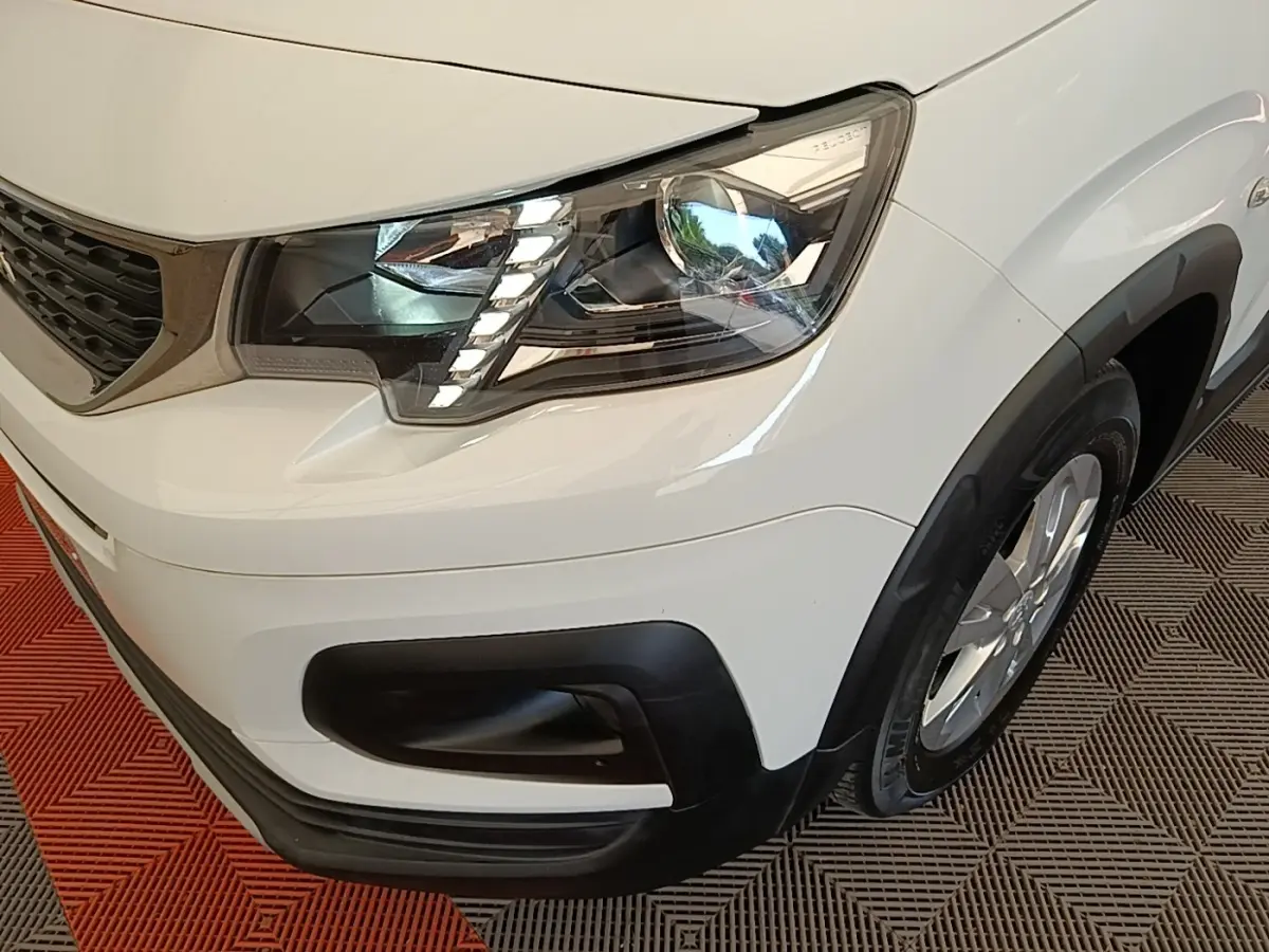 Gros plan sur l'avant droit blanc du Peugeot Rifter 2020, mettant en valeur le phare LED et la calandre noire.