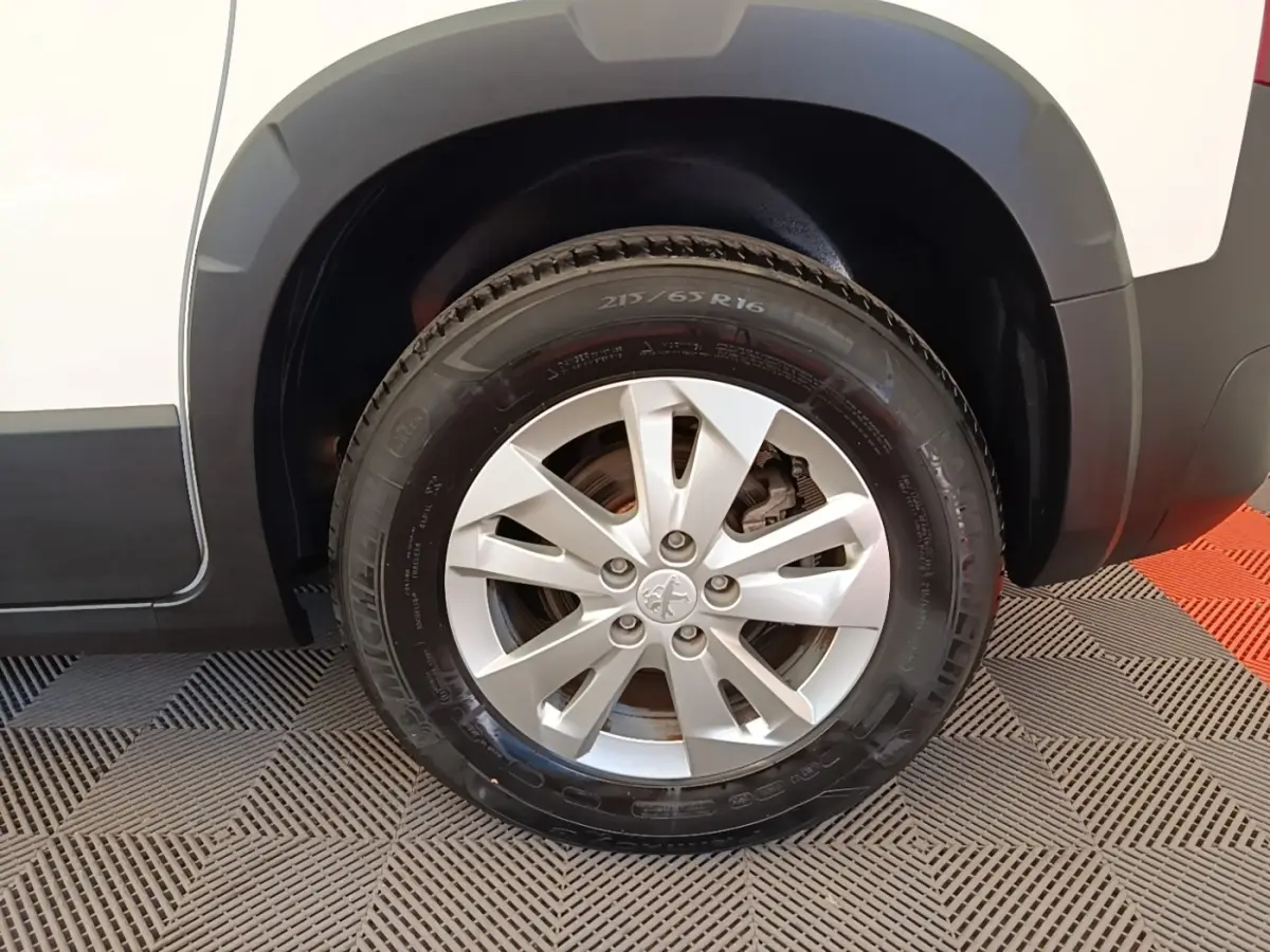Gros plan sur la roue avant droite d’un Peugeot Rifter blanc, avec jante alliage et pneu Michelin visible.