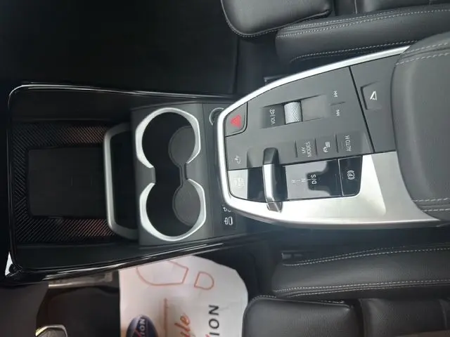 Gros plan sur la console centrale en cuir noir avec commandes de boîte auto et porte-gobelets du BMW X1 Storm Bay 2024