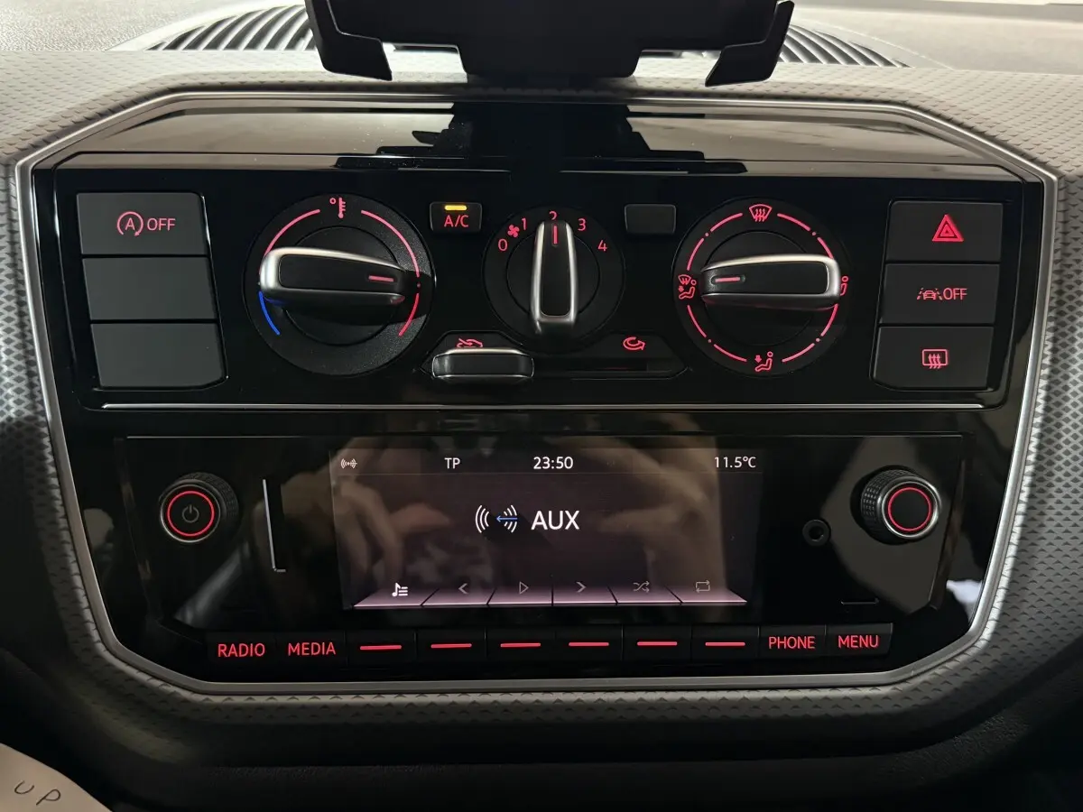 Vue rapprochée du tableau de bord noir brillant de la Volkswagen Up 1.0 65 Active avec commandes climatisation et écran multifonction.