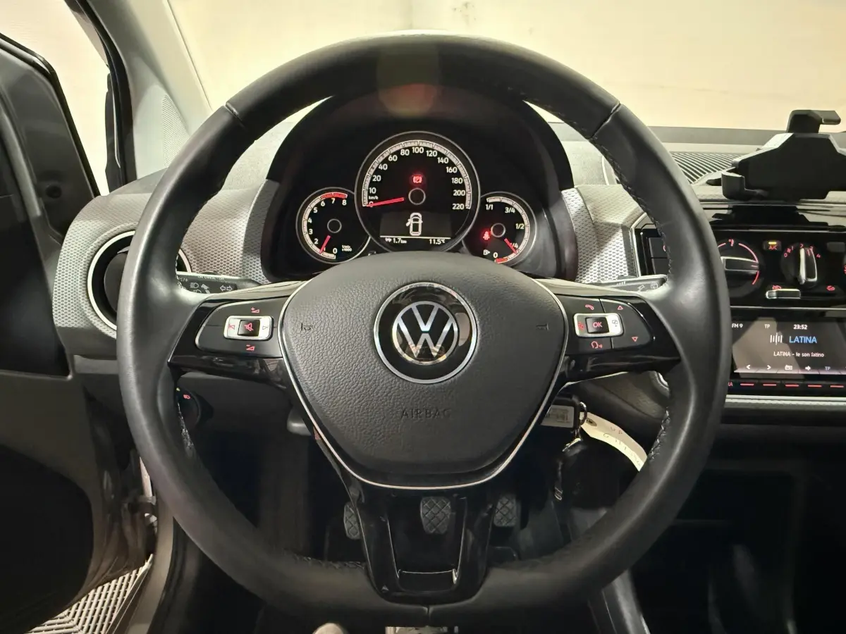 Vue intérieure centrée sur le volant cuir noir et le tableau de bord du Volkswagen Up 1.0 65 Active 2022.