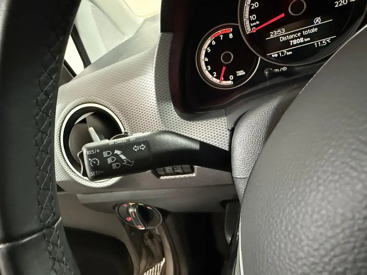 Gros plan sur le volant cuir et le combiné d'instruments du Volkswagen Up gris foncé, côté gauche du tableau de bord.