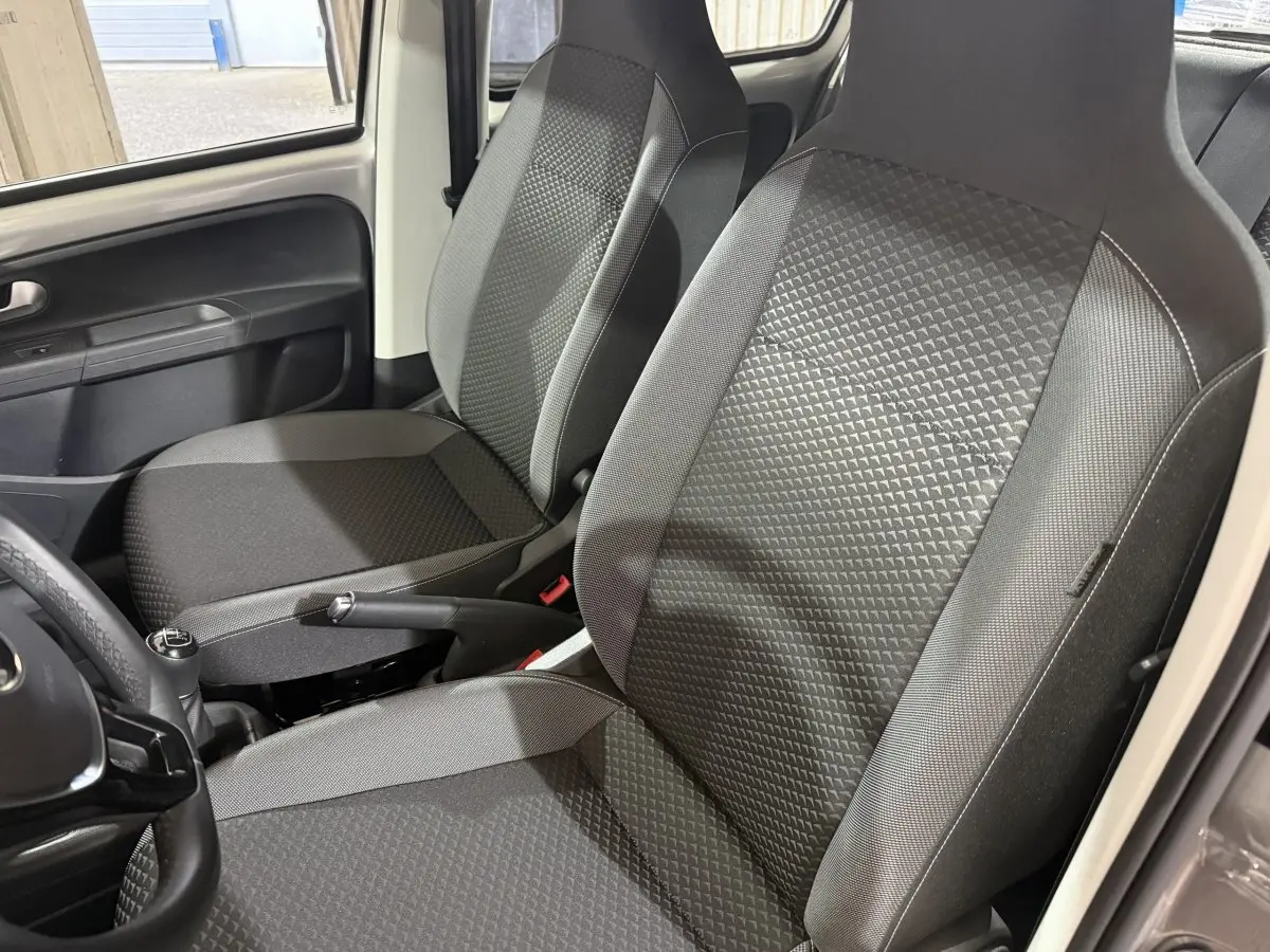 Vue rapprochée des sièges avant gris foncé et de la console centrale d'une Volkswagen Up 1.0 65 Active 2022.