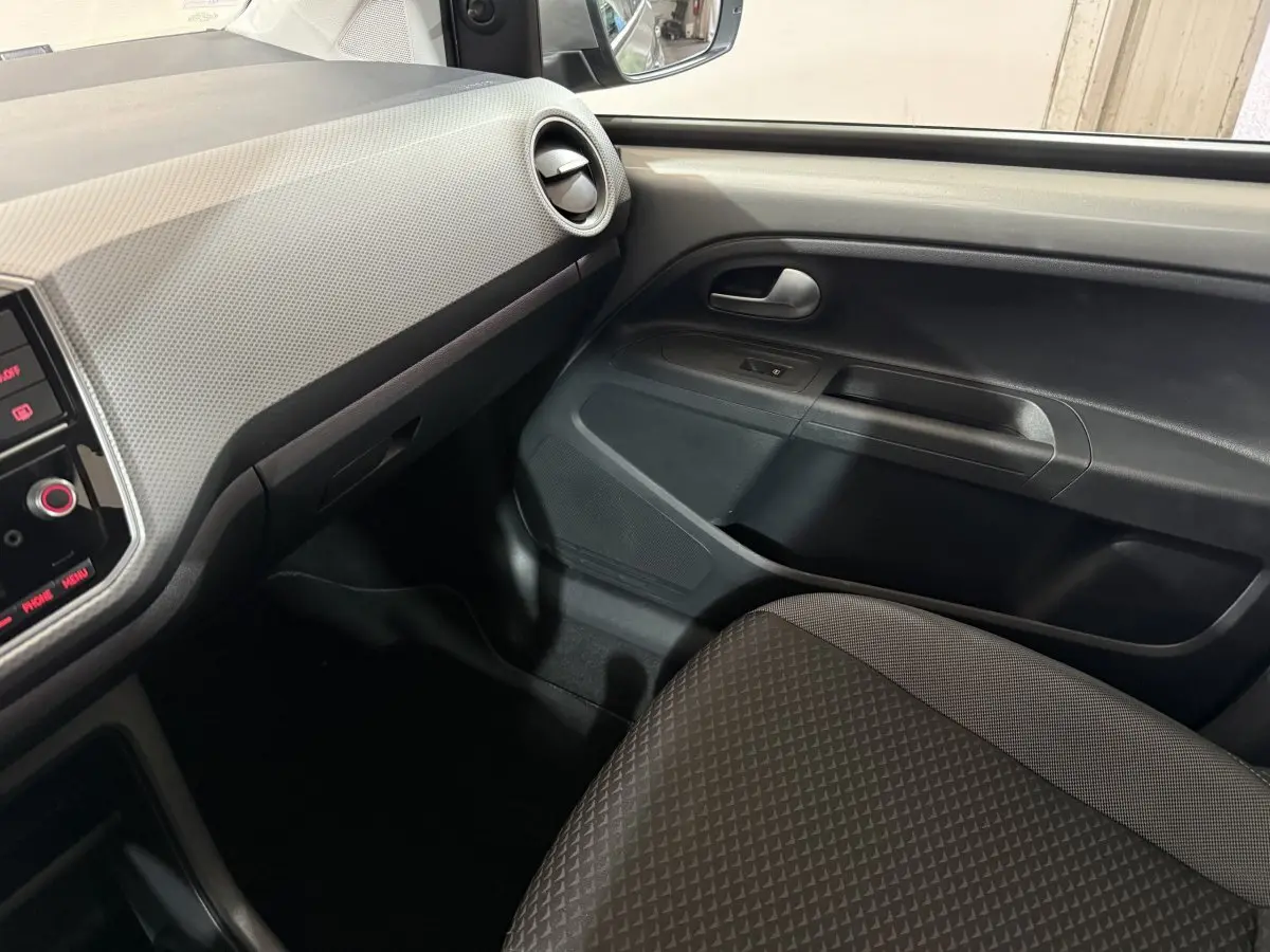 Intérieur côté passager de la Volkswagen Up 1.0 65 Active 2022, montrant la porte et tableau de bord gris foncé.