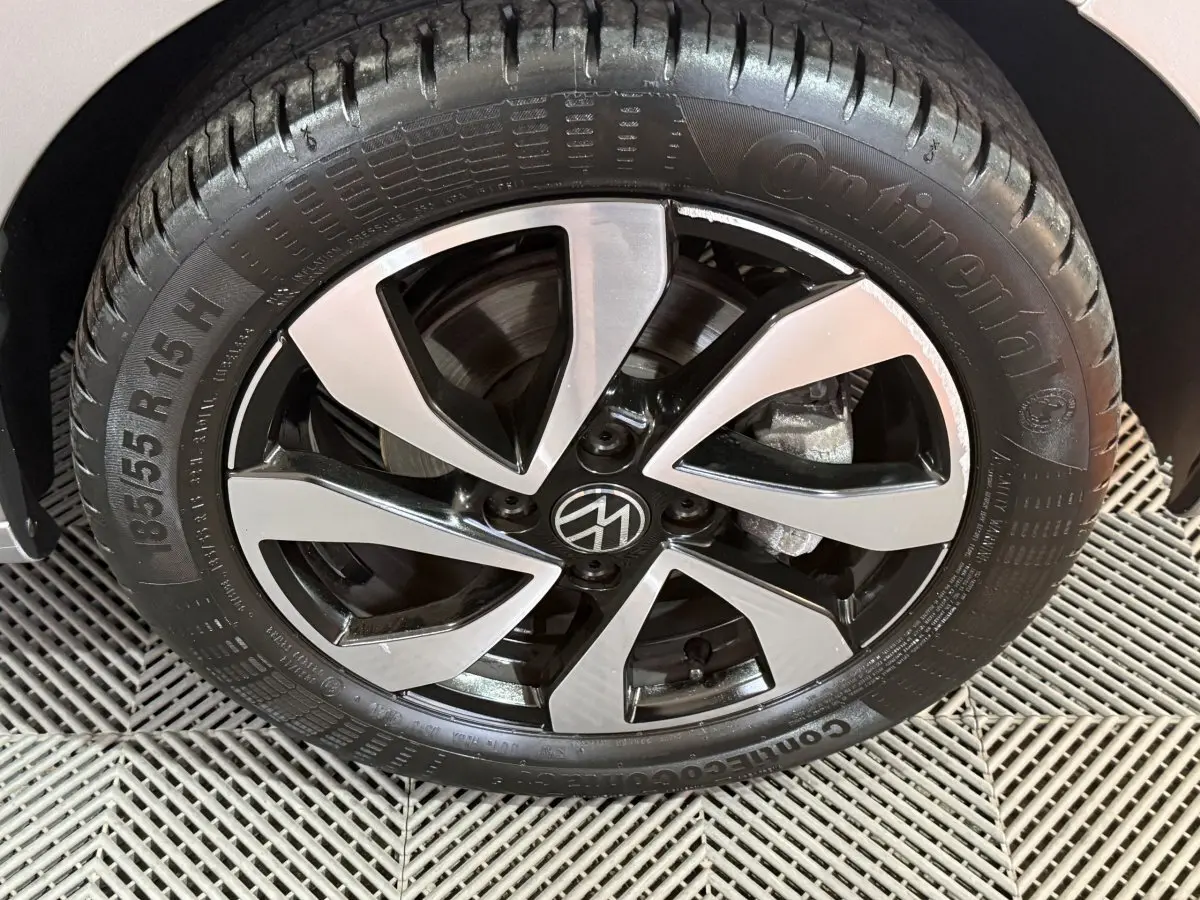 Gros plan sur la roue avant droite d'une Volkswagen Up gris foncé avec jante alliage noire et argentée au design moderne.