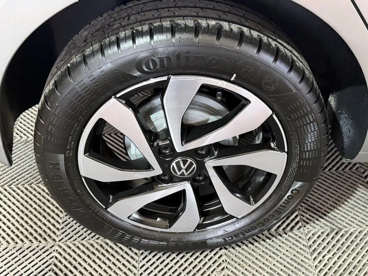 Gros plan sur la roue avant droite d'une Volkswagen Up gris foncé avec jante alliage bicolore et logo VW central.