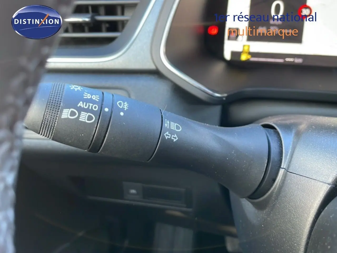 Gros plan sur la commande des feux à gauche du volant dans l’habitacle gris noir du Renault Captur 2025 bicarburation.