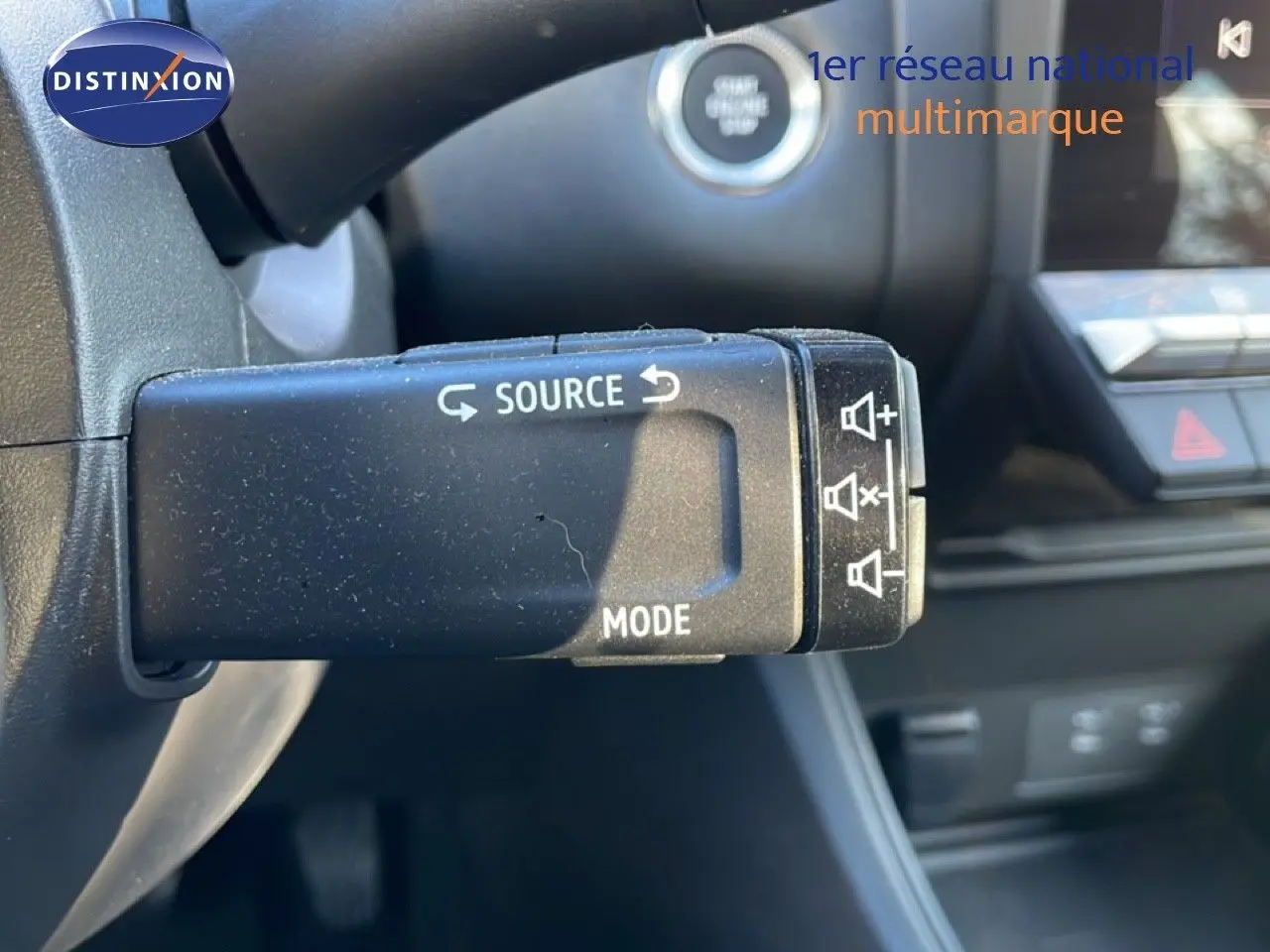 Gros plan sur la commande audio au volant d'un Renault Captur gris Rafale métal avec toit noir, intérieur moderne.