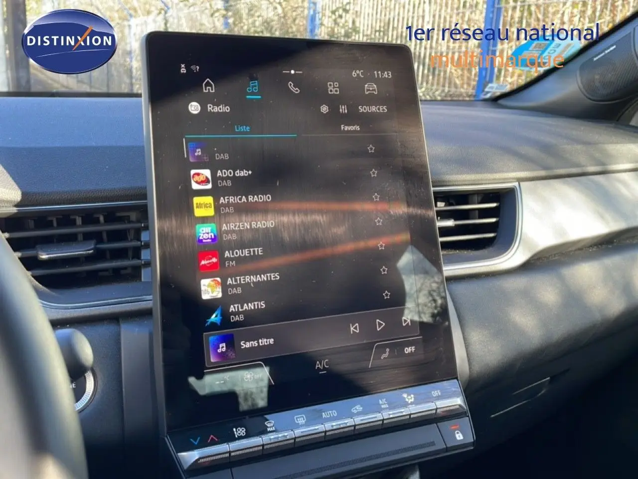 Vue intérieure du tableau de bord du Renault Captur 2025, écran tactile central affichant les radios DAB, ambiance grise et noire.