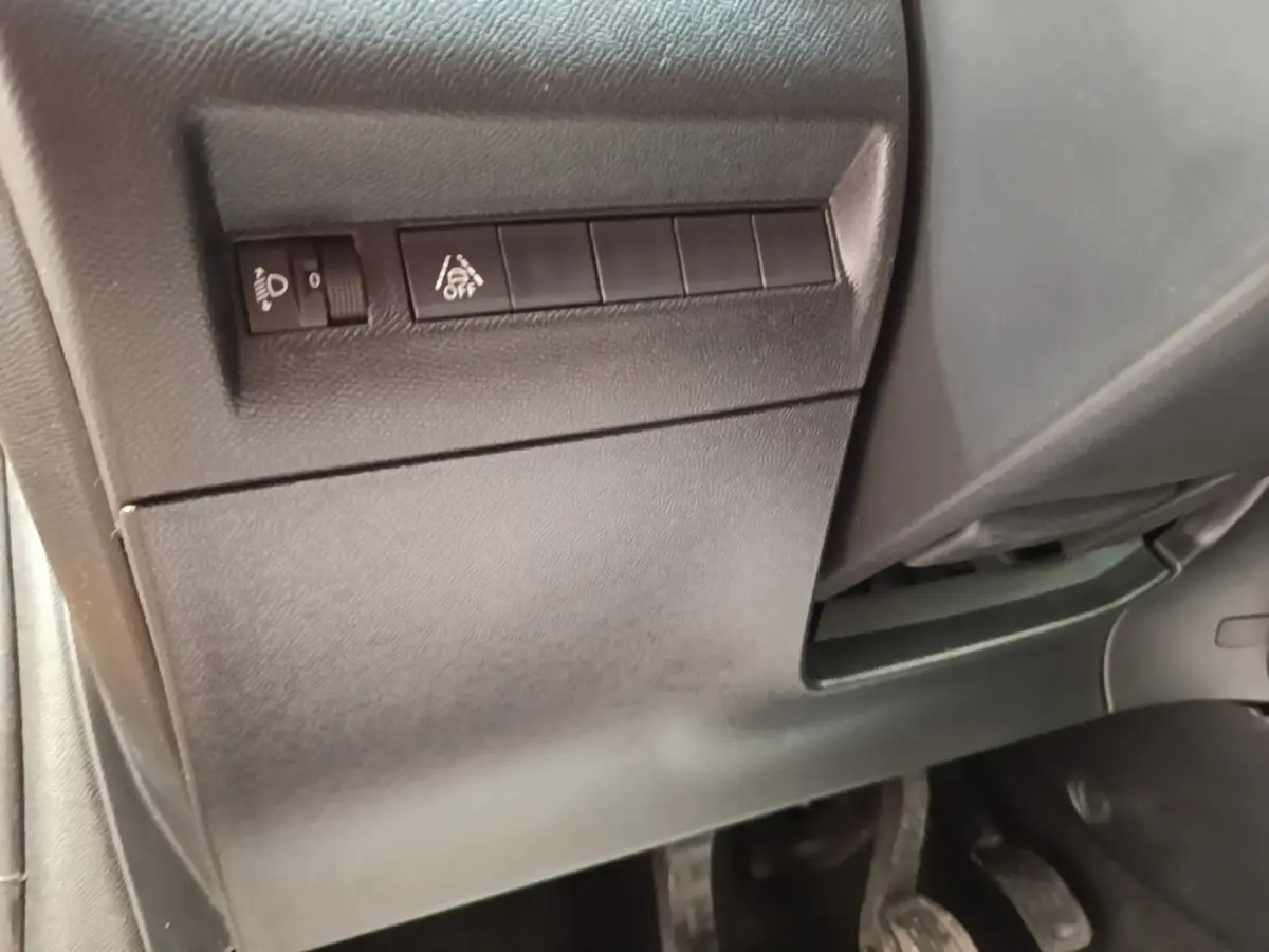 Vue intérieure côté conducteur du tableau de bord bas avec commandes de réglage des phares et d'assistance à la conduite.