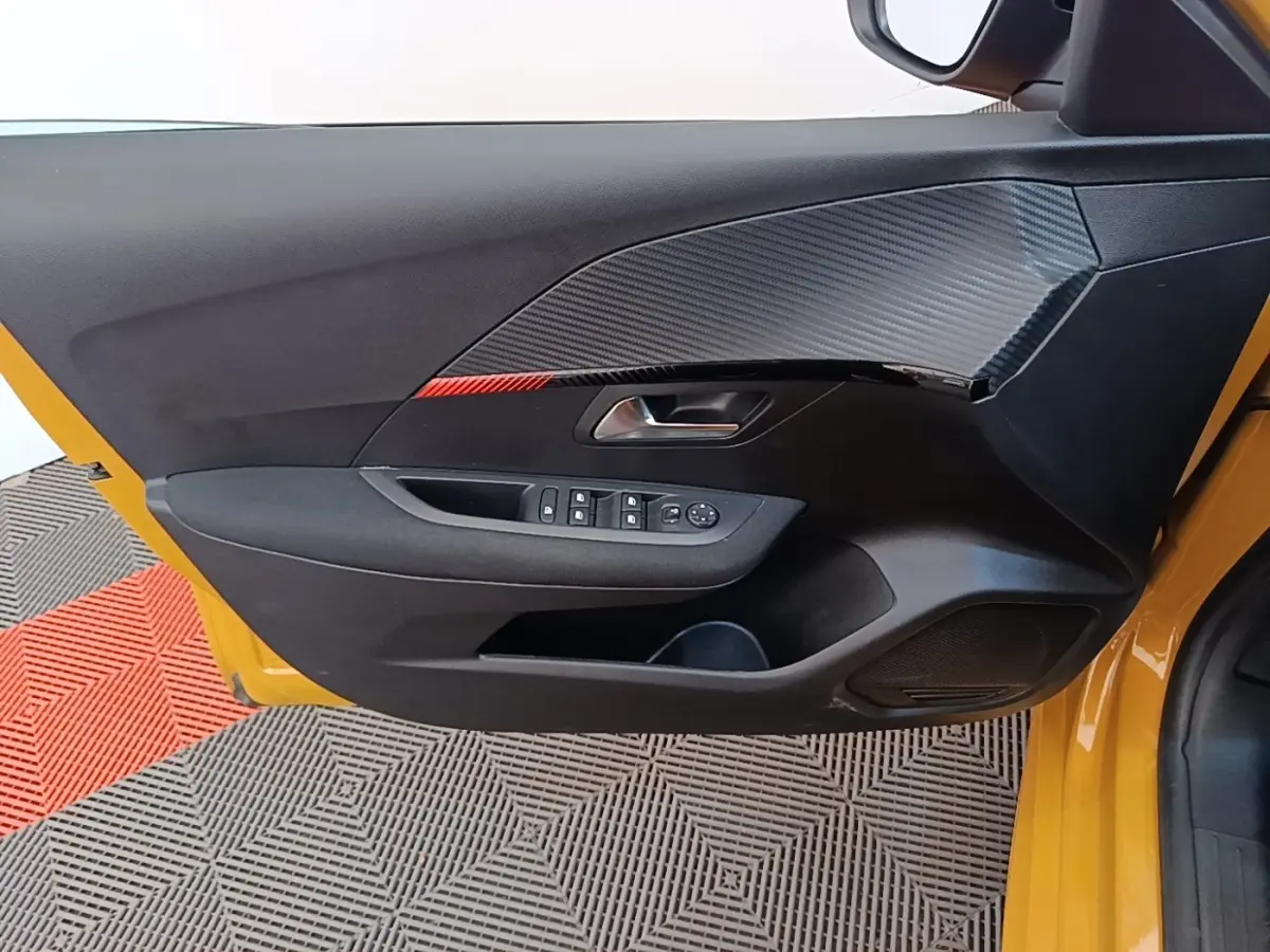 Vue rapprochée de la porte avant gauche jaune d'une Peugeot 208 2023, avec commandes électriques et insert décoratif noir.