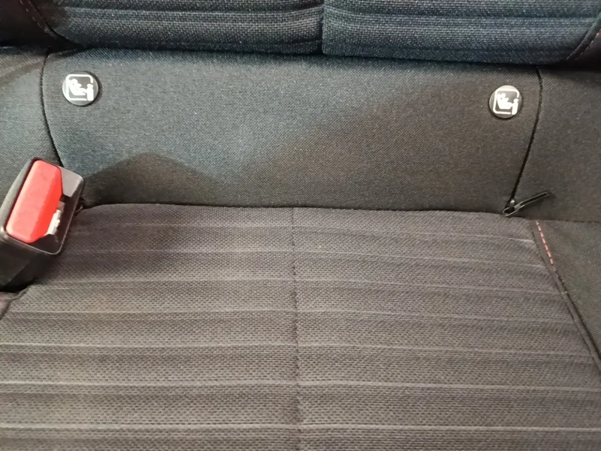 Gros plan sur la banquette arrière noire de la Peugeot 208, avec boucle de ceinture rouge et fixations Isofix visibles.